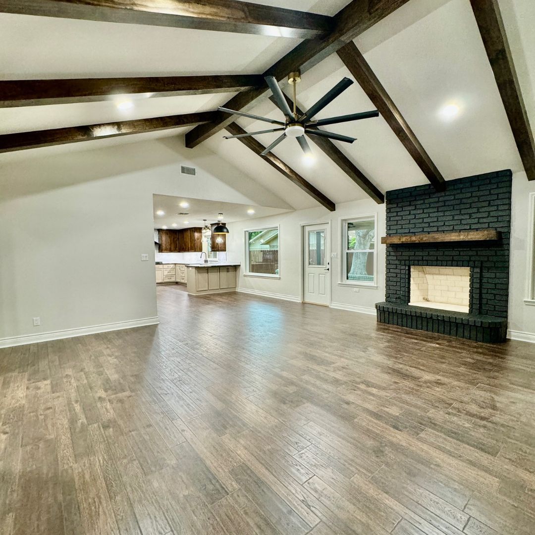 Family Room / Living room with wood beams and vaulted ceiling. Brick fireplace painted Iron Ore by Sherwin Williams. Luxury vinyl plank flooring by Pergo. Wall color is Aesthic White by Sherwin Williams.