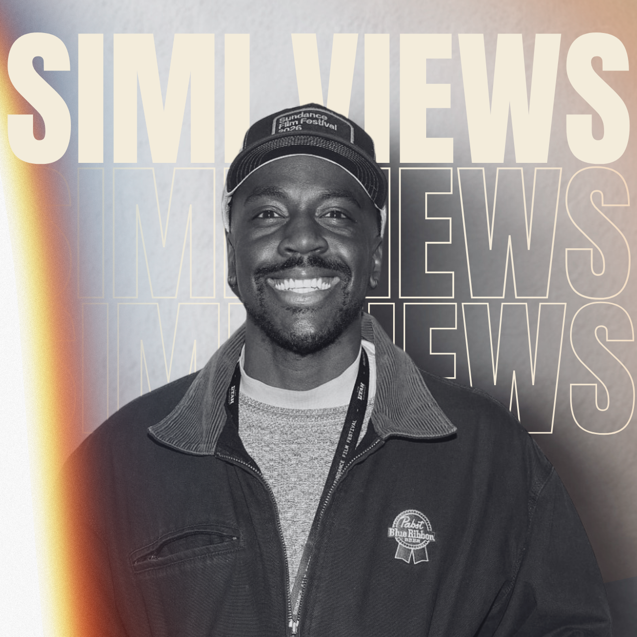 A smiling man wearing a cap and a jacket with a lanyard, standing in front of a background with large repeated text that says 'SIMI VIEWS'.