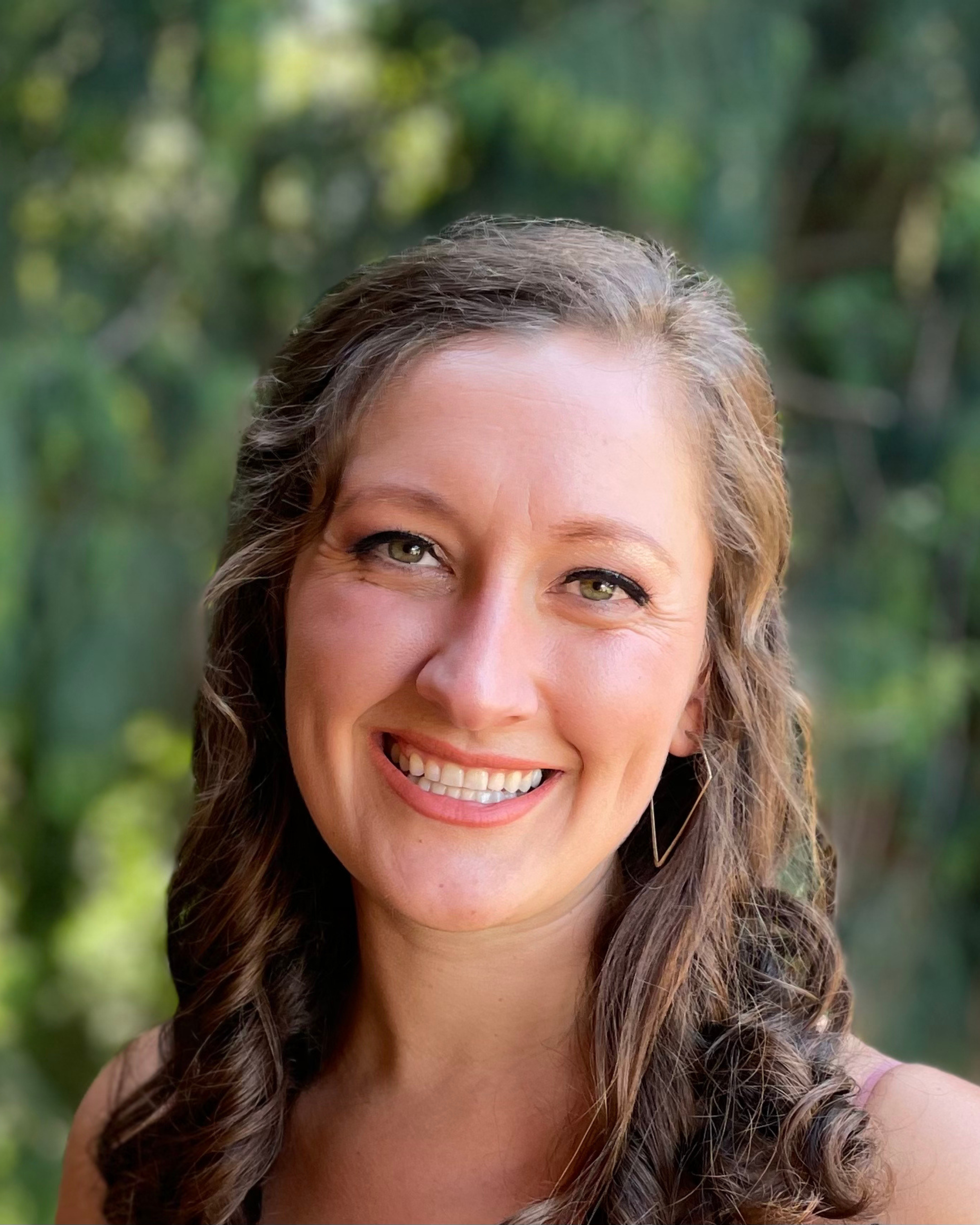 Headshot of Elizabeth Langford, LPC, smiling outdoors with a blurred green background.