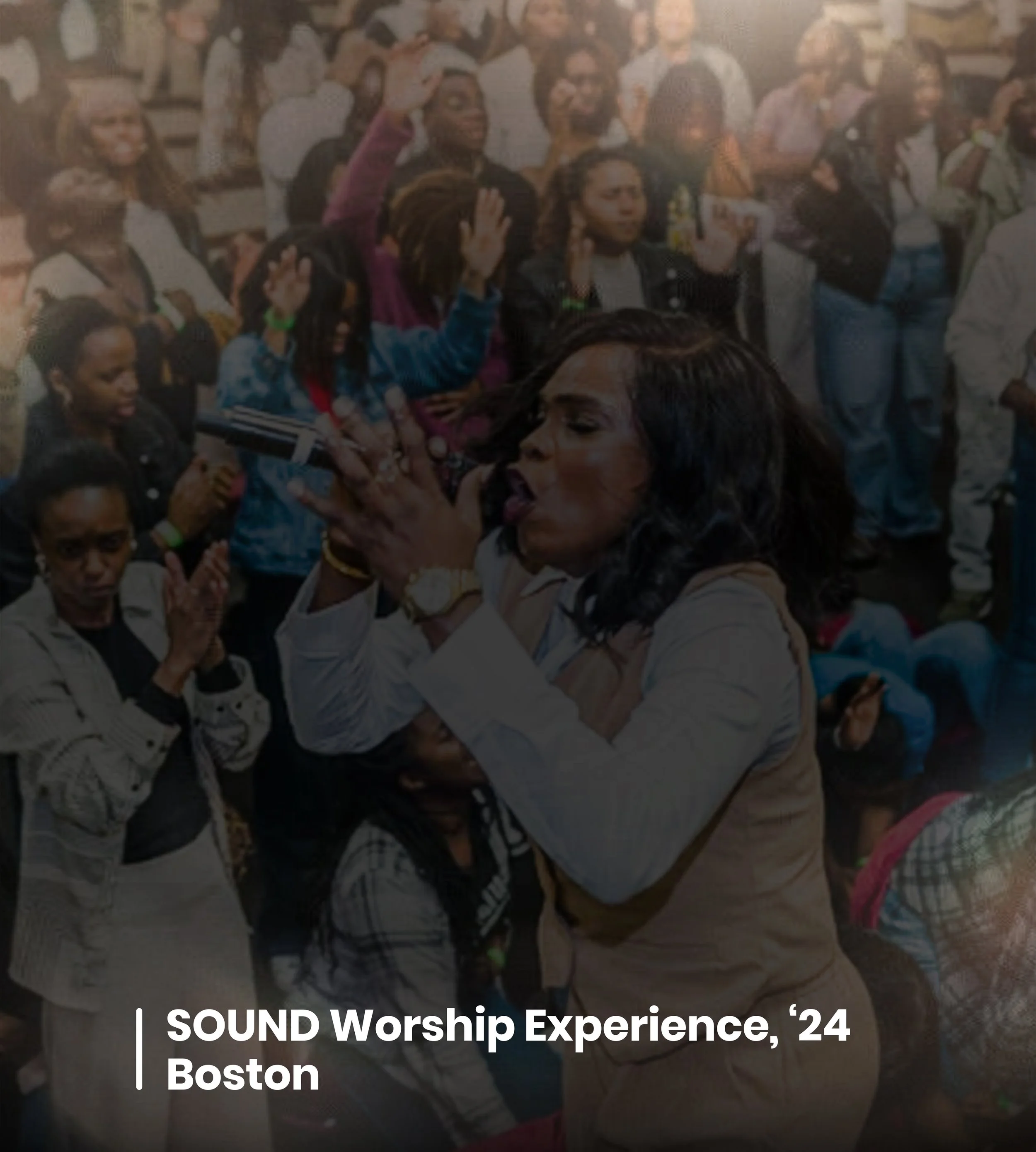 A group of people gathered in a church, singing and raising hands in worship during a sound worship experience in Boston in 2024.