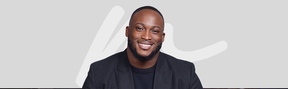 Smiling man in black blazer against gray background