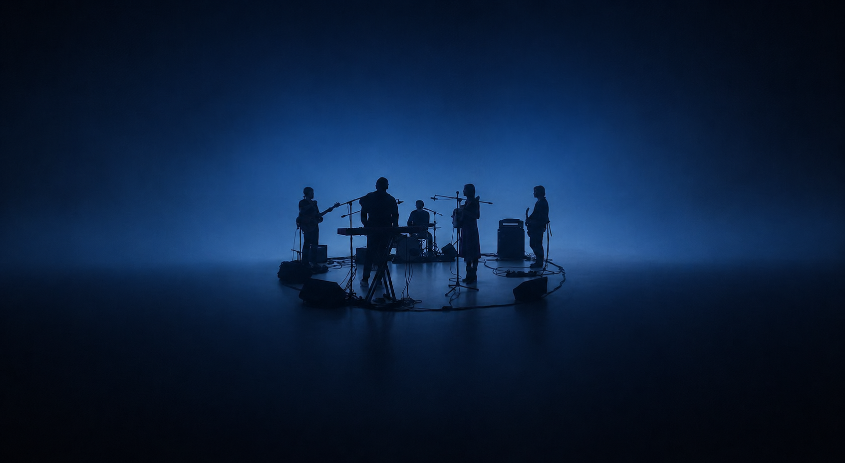 Silhouettes of a band performing with instruments in a dark, blue-lit space.