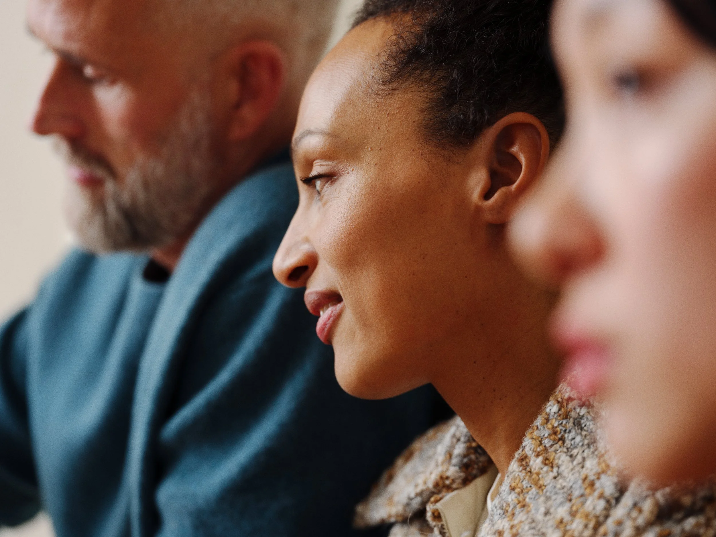 Close-up of three people sitting side by side with their eyes closed, appearing to be meditating or resting.