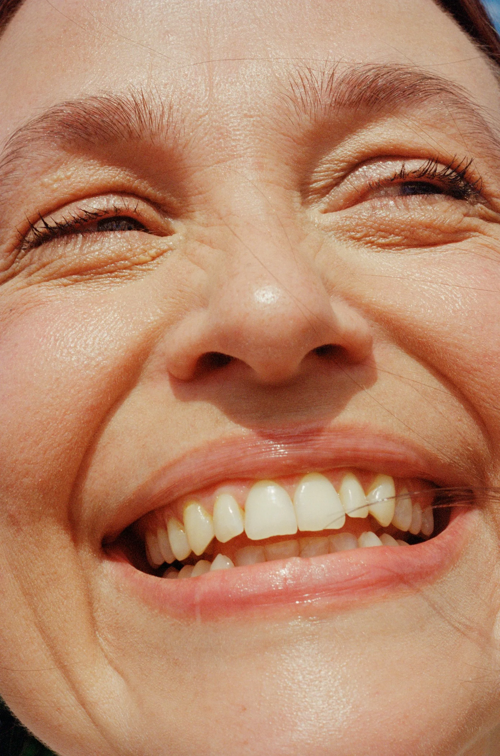 Close-up of a smiling person's face, showing their eyes, nose, and mouth with visible teeth.