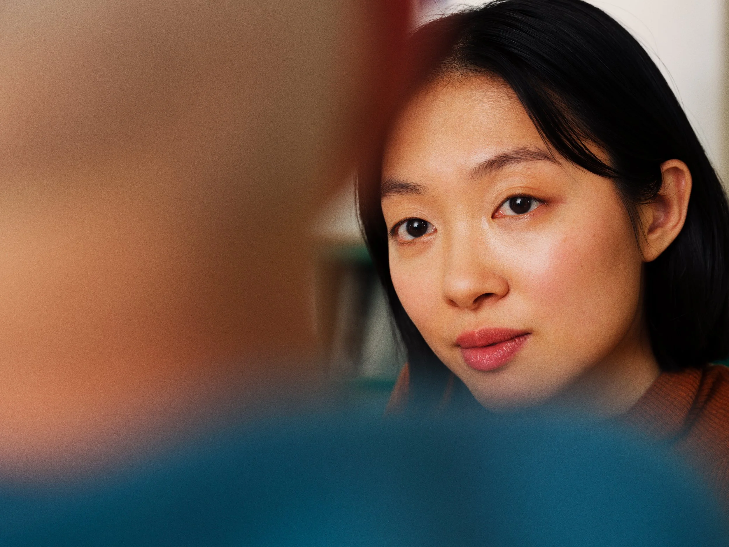 Close-up of a young Asian woman with black hair, looking attentively at something or someone outside the frame.