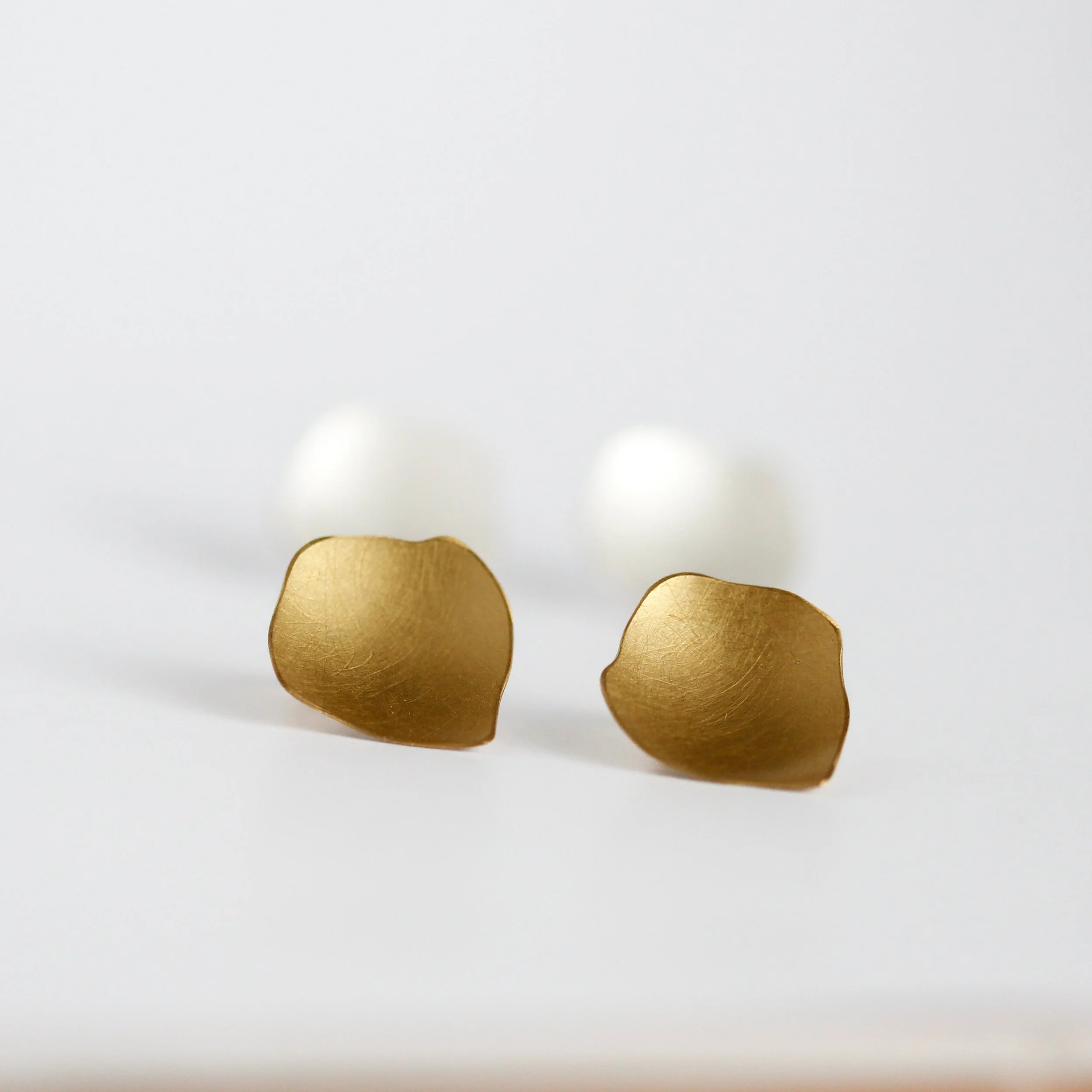 Close-up of several gold-colored earings on a white surface.