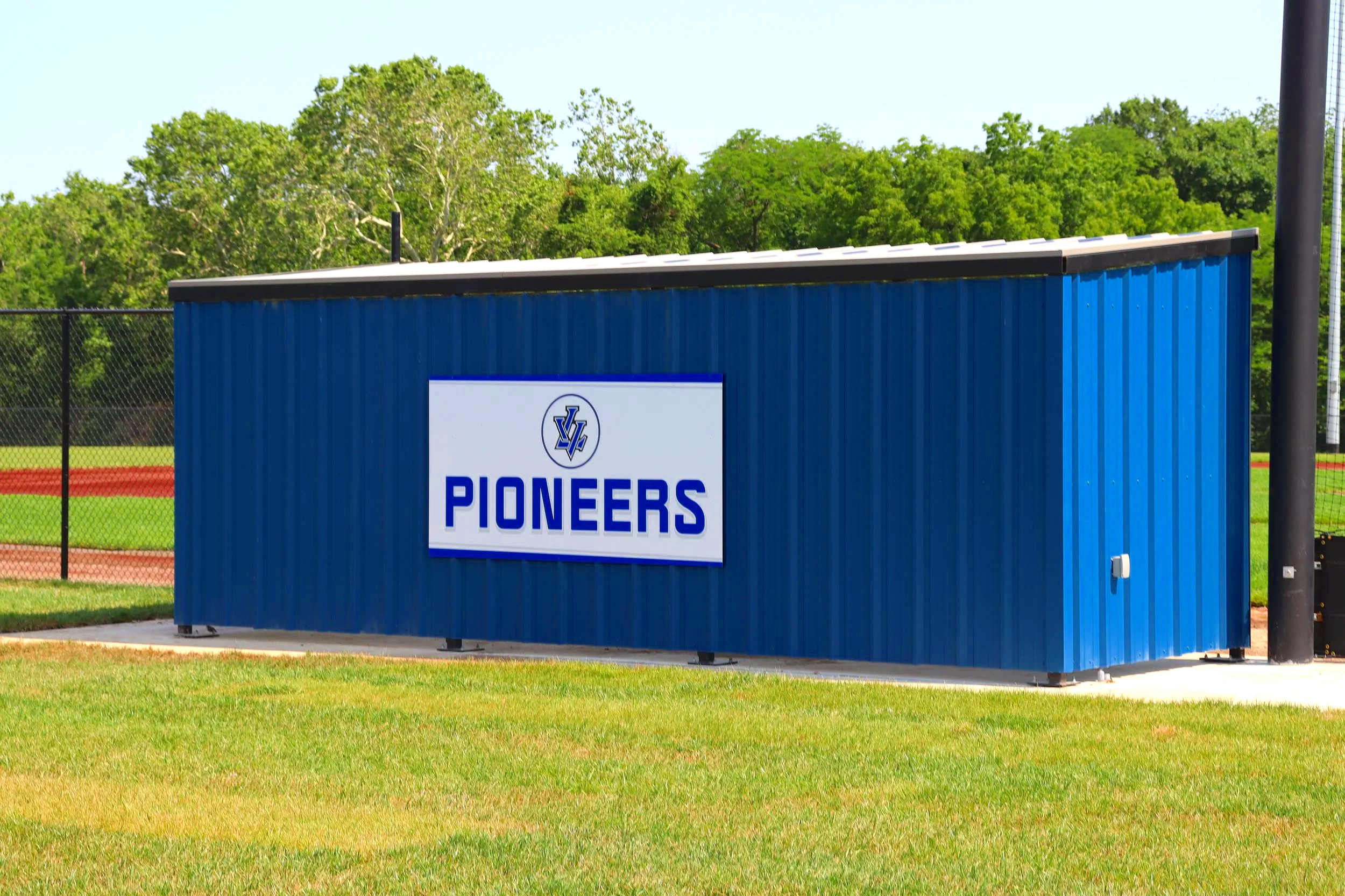 Custom Pioneers team branding panel on blue dugout exterior at baseball facility