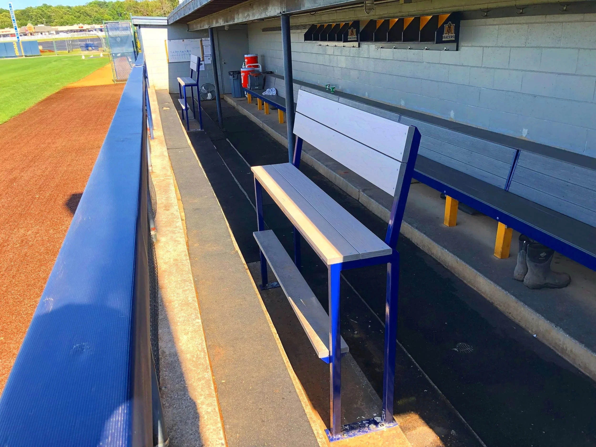 Blue painted Elite bench seating installed in college baseball dugout facility — USS athletic facility benches supplier for college athletic programs and university sports facilities