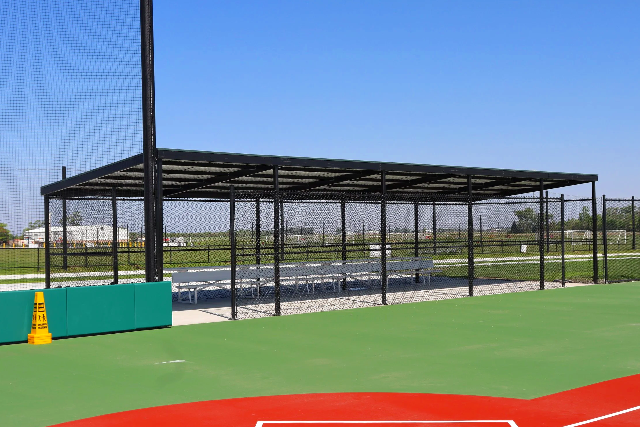 Fielder's Choice PRO baseball dugout with bench seating and barrier netting at EAA athletic facility in Elkhorn Nebraska — USS baseball dugout supplier