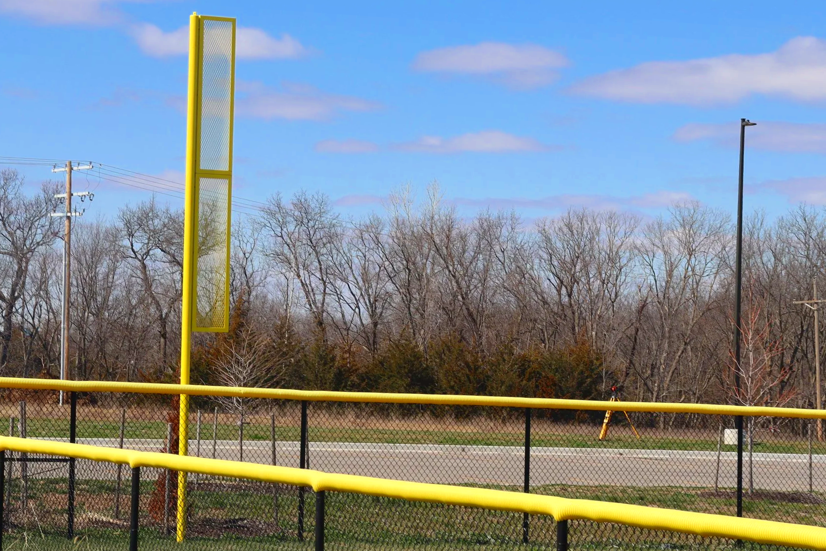 Yellow fence cap on chain link fence at foul pole junction on baseball field