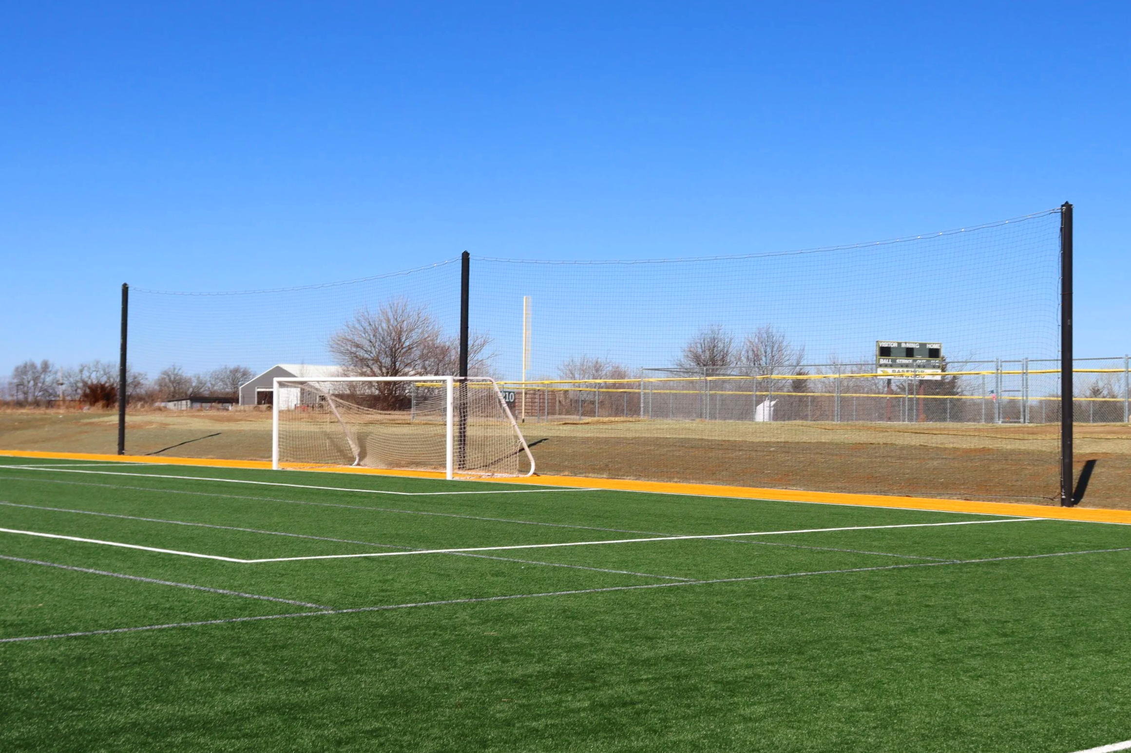 Soccer field perimeter netting and chain link fencing with Garmin sponsorship signage at sports complex in Olathe Kansas