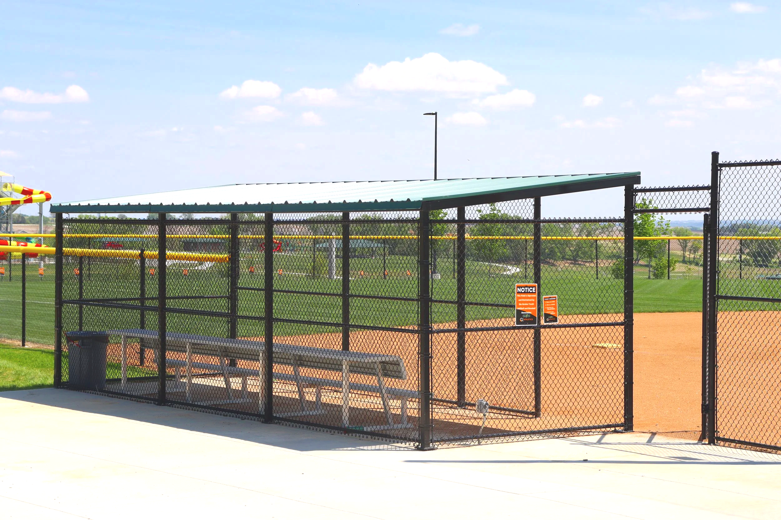 Fielder's Choice PRO baseball dugout with bench seating and green metal roof at Gretna Crossing athletic facility in Gretna Nebraska — USS baseball dugout supplier