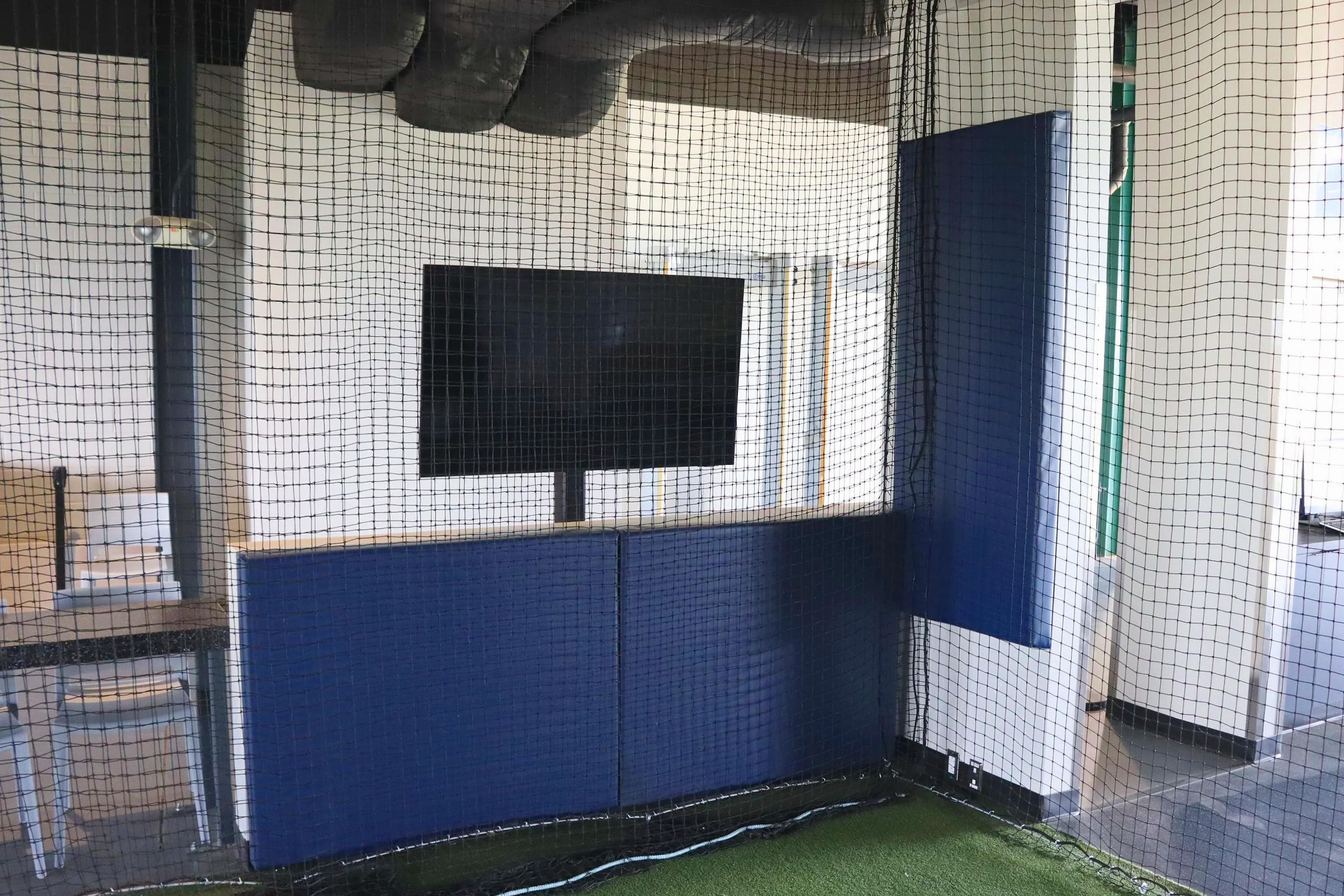 Blue indoor wall padding and barrier netting system installed at Sugar Land indoor baseball training facility for the Houston Astros organization in Texas — USS sports field padding supplier and indoor athletic facility padding supplier protecting pr