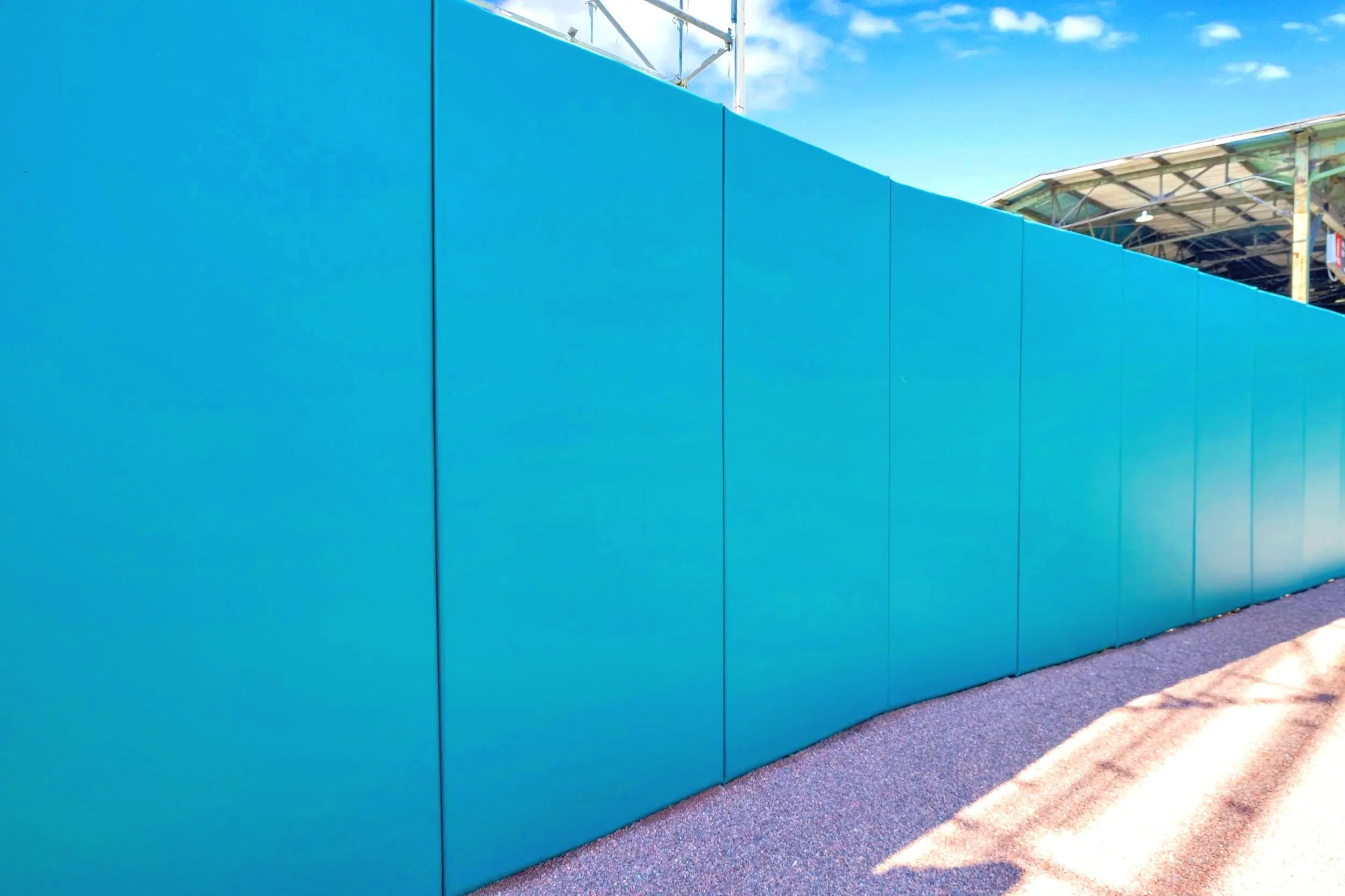 Bright teal exterior wall padding covering full height and length of outfield wall at historic Rickwood Field in Birmingham Alabama with warning track surface below — USS exterior wall padding supplier and sports field padding supplier providing comp