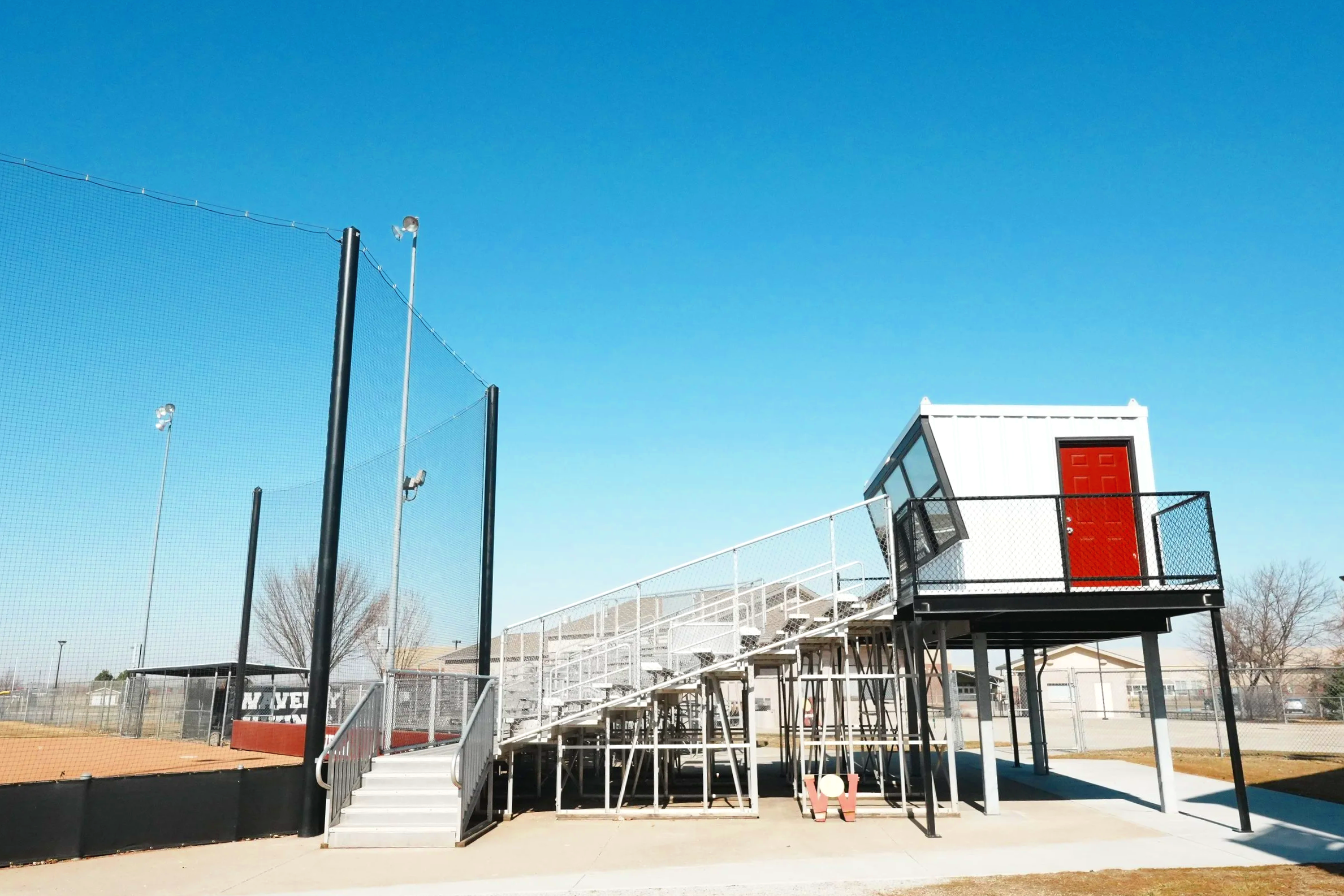 The USS press box with red door elevated above the grandstand at Waverly High School in Waverly, Nebraska — professional press box construction integrated alongside aluminum bleachers and barrier netting from one complete athletic facility supplier. 