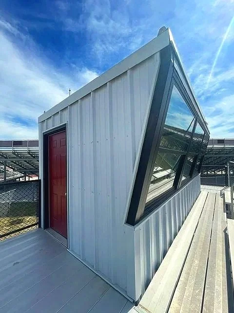 A close-up exterior view of the USS press box unit at Waverly High School in Waverly, Nebraska — professional prefab press box construction with panoramic windows, red door entry, and built-in electrical and HVAC included. Ready to install, ready to 