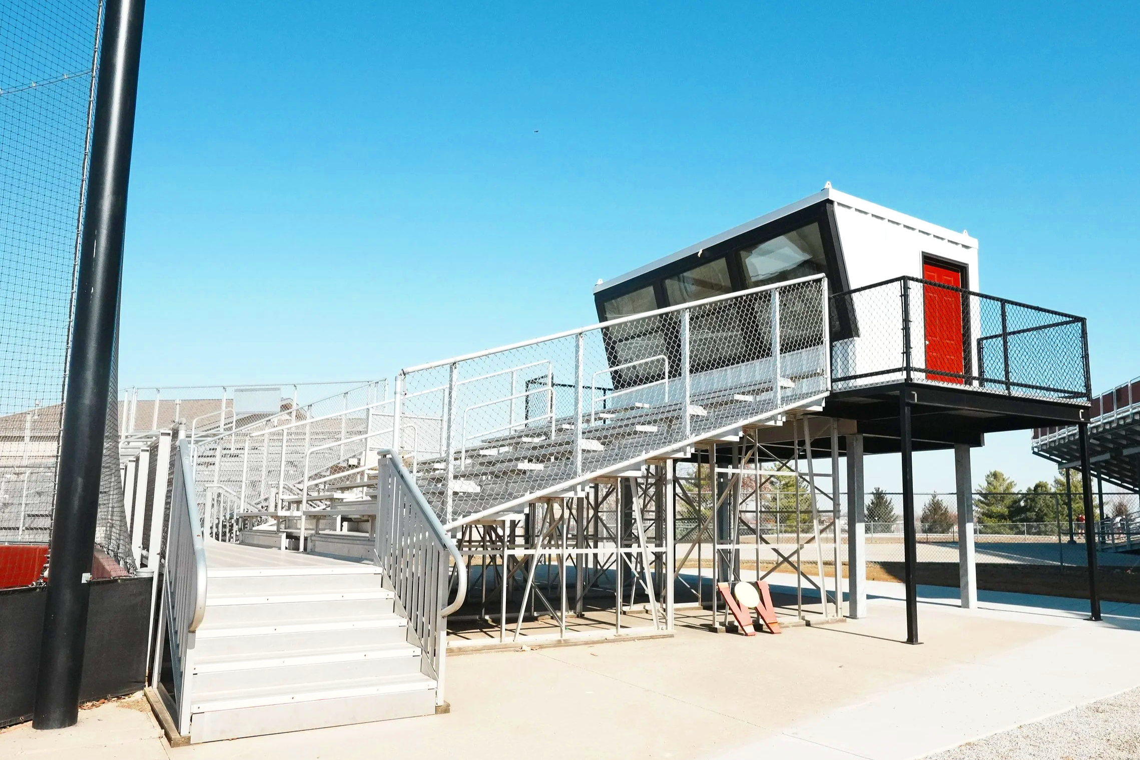 A close-up exterior view of the USS press box unit at Waverly High School in Waverly, Nebraska — professional prefab press box construction with panoramic windows, red door entry, and built-in electrical and HVAC included. Ready to install, ready to 