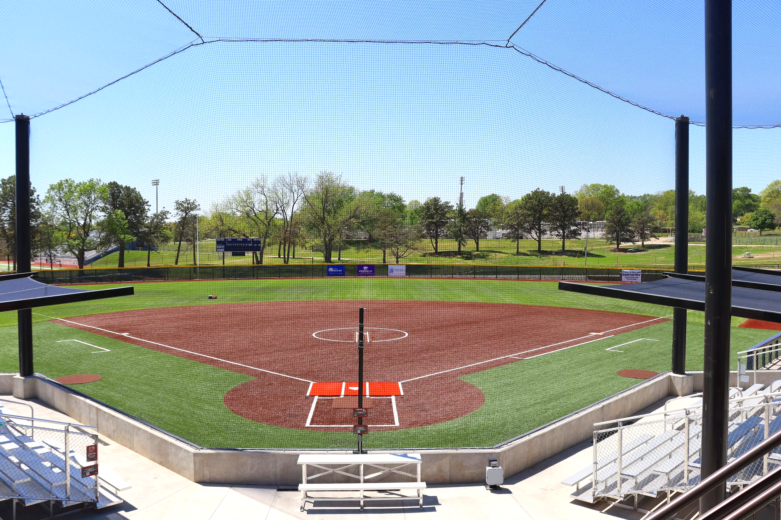Complete baseball field at Cico Park, Kansas with backstop netting, bleachers, and artificial turf