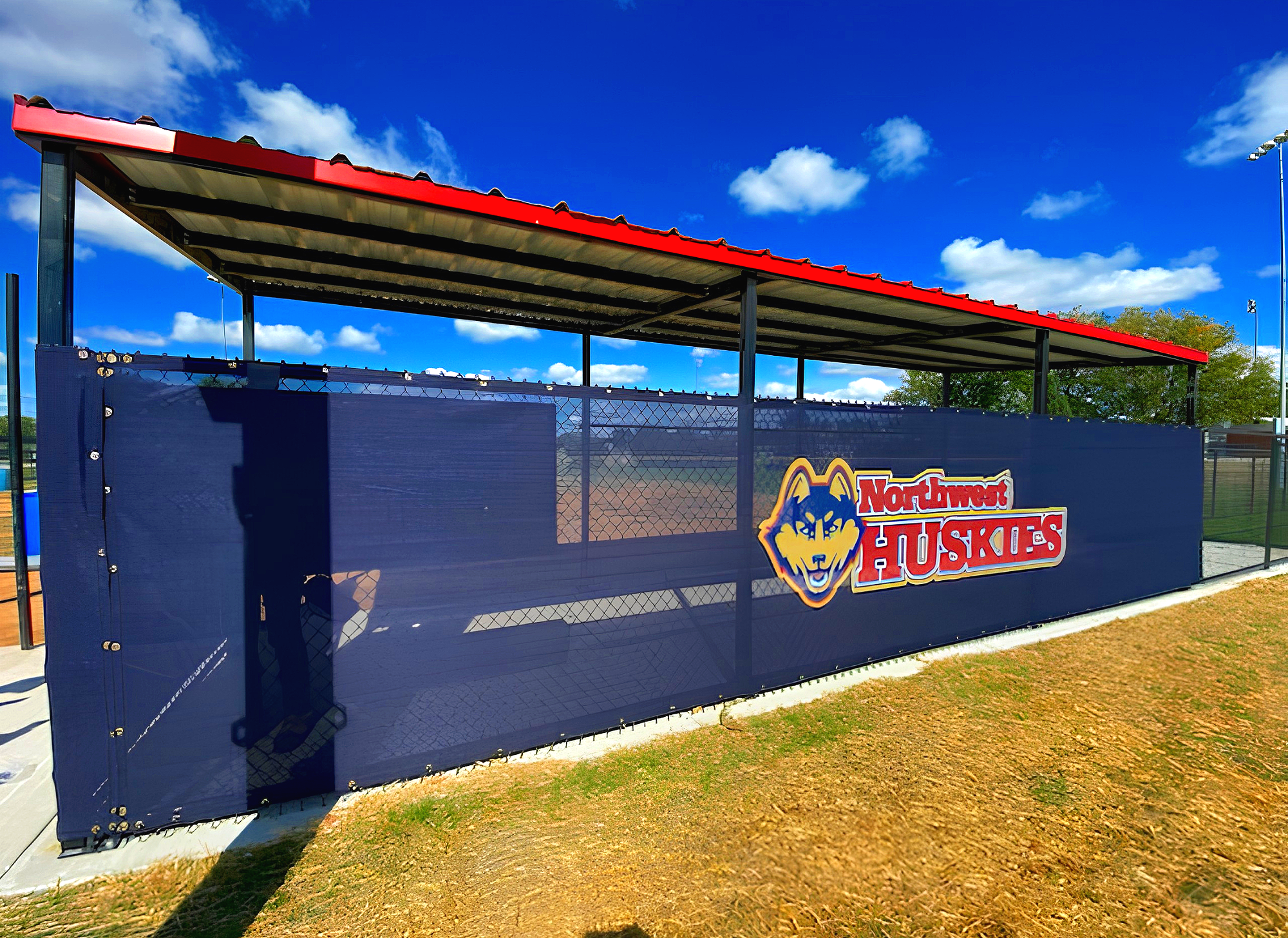 Northwest Huskies branded windscreen on baseball dugout at Omaha Northwest High School