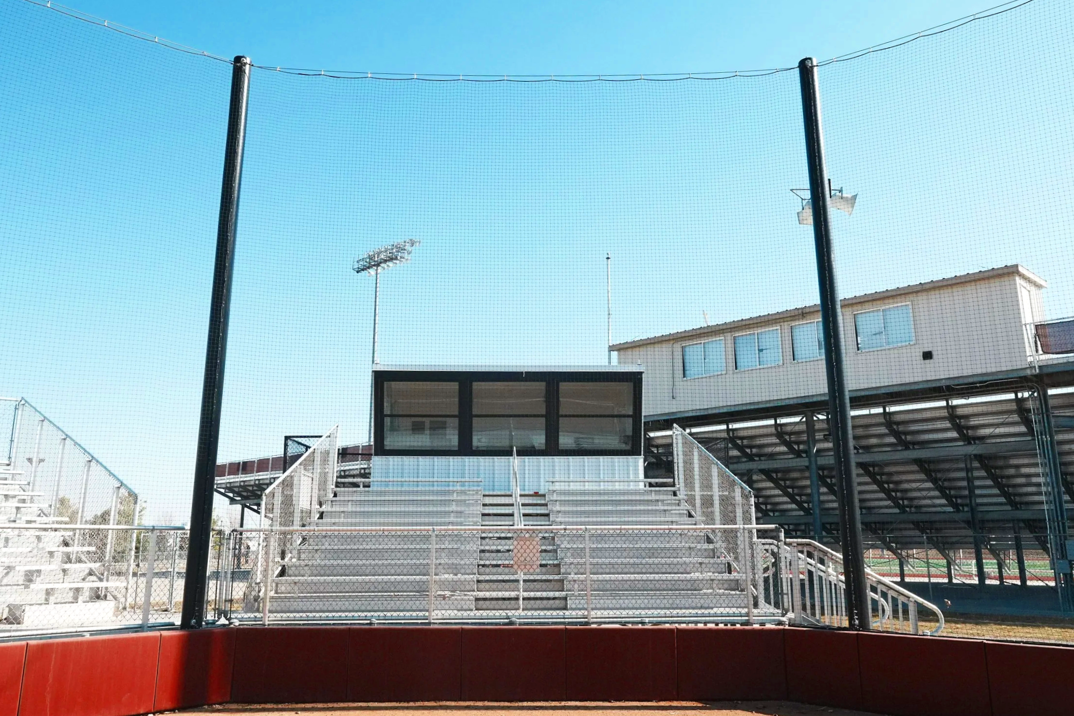 USS press box installed above aluminum bleacher grandstand with barrier netting at Waverly High School softball field in Waverly Nebraska — USS baseball press box supplier for high school athletic programs