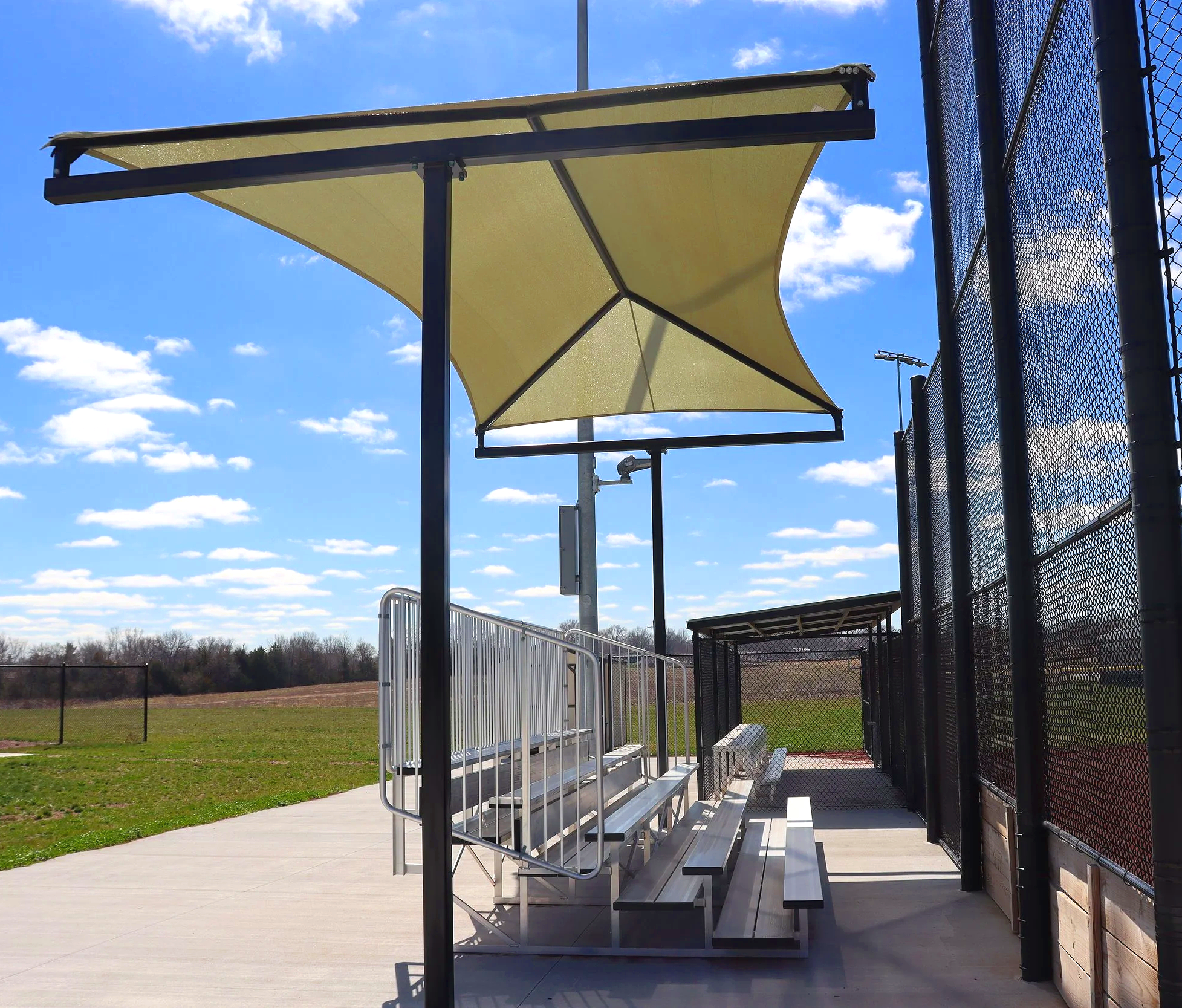 T-Post shade structure over aluminum bleacher seating at athletic baseball facility in Cameron Missouri — USS shade structures for athletic fields supplier