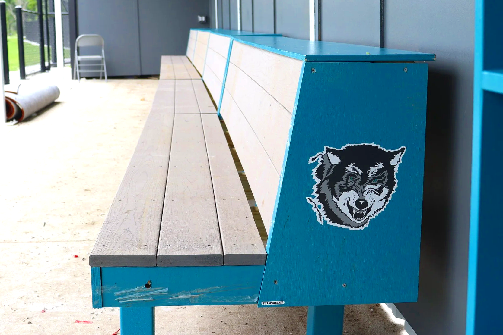 Custom team logo branding on youth baseball dugout bench for little league athletic program