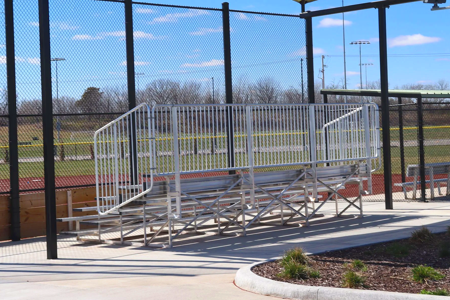 Low maintenance aluminum bleachers with handrail and aisle stairway at outdoor baseball field — USS aluminum bleachers supplier for schools parks departments and municipalities