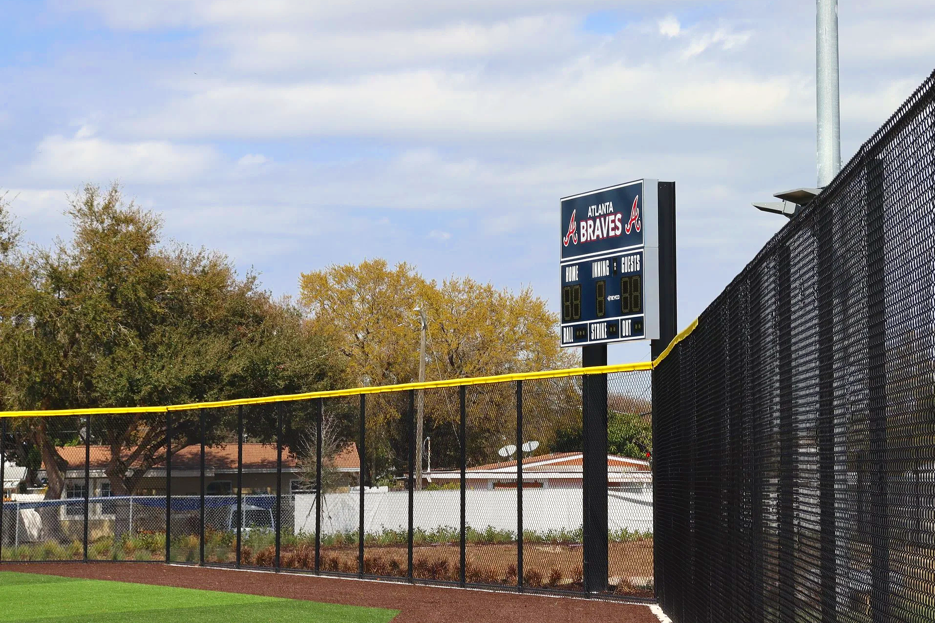 : Yellow fence cap on black chain link outfield fence at Atlanta Braves youth baseball complex, Pinellas Park, Florida