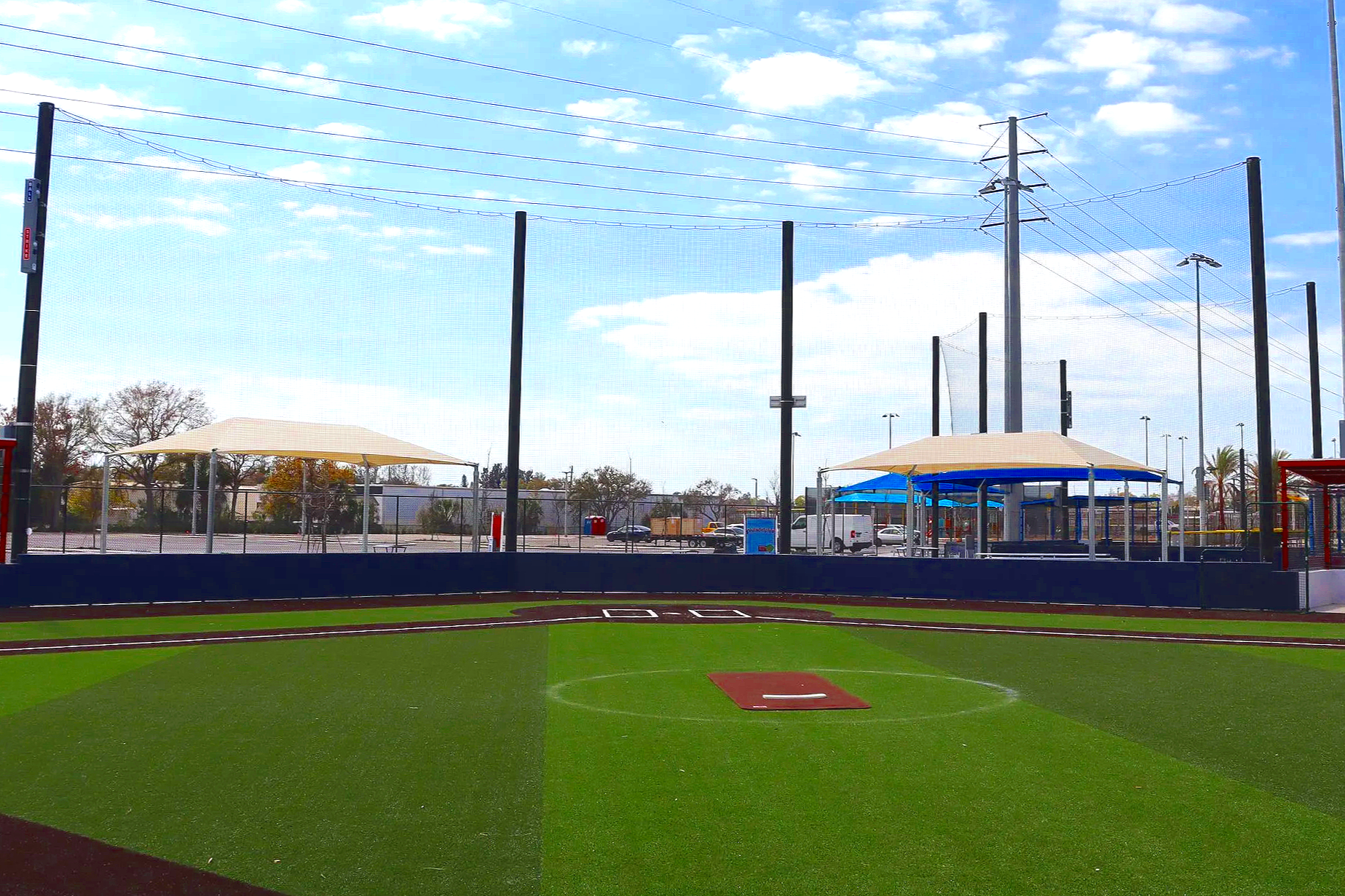 Portable pitching mound on synthetic turf baseball field with barrier netting shade structures and stadium lighting — USS portable pitching mound supplier