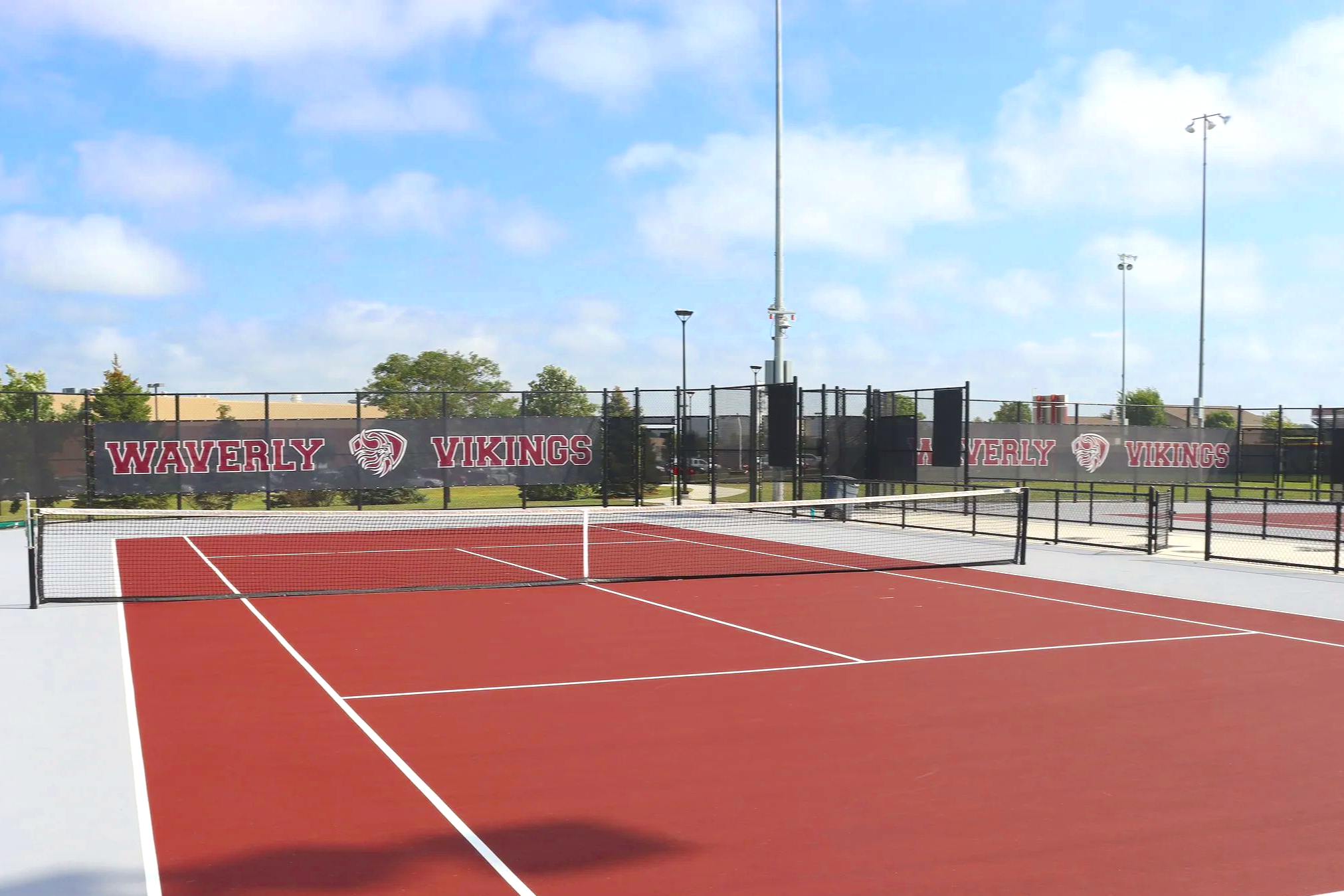 Custom Waverly Vikings branded windscreen on tennis court fence at high school athletic facility