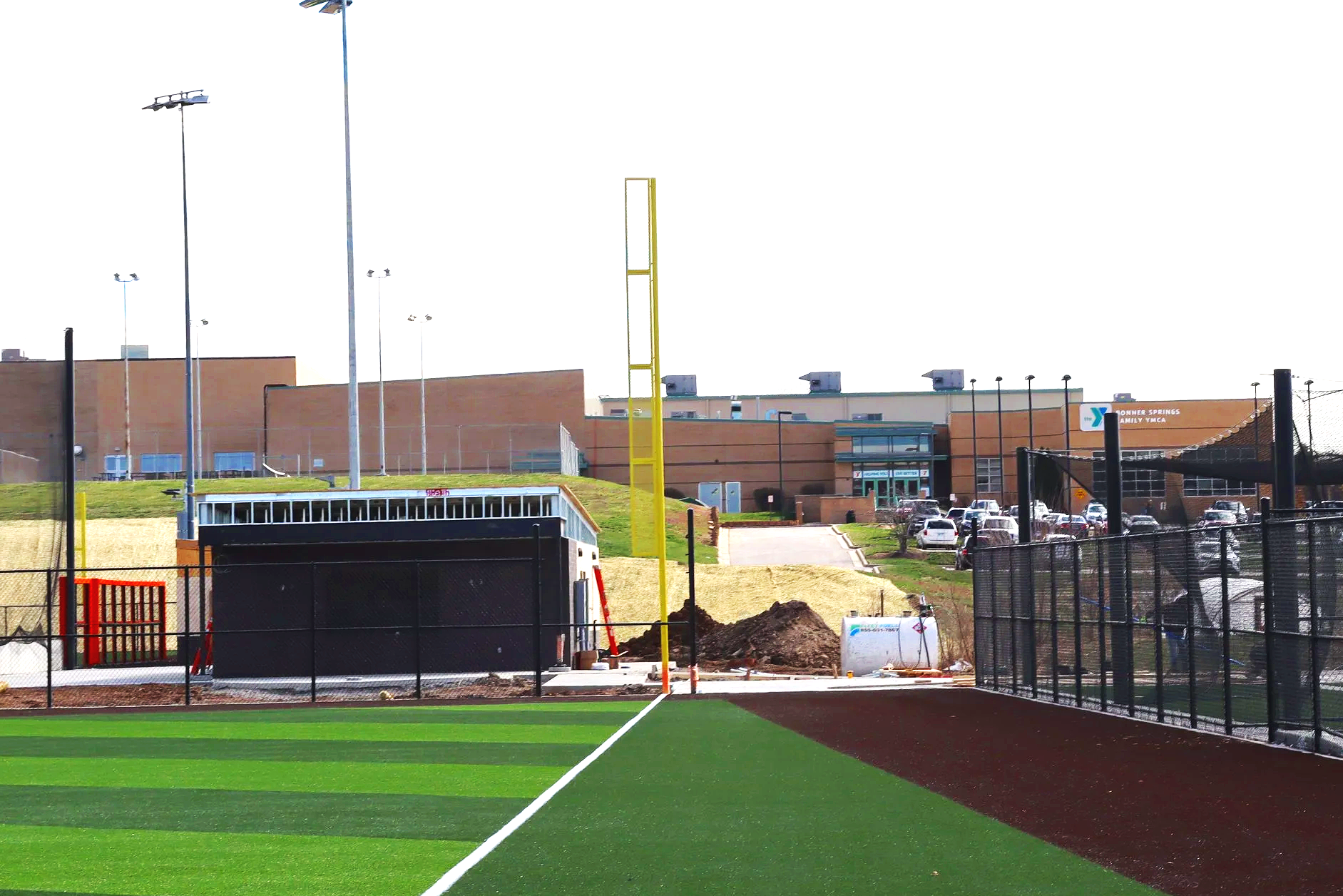 Yellow baseball foul pole installed during new construction at Bonner Springs Kansas athletic complex with batter's eye and synthetic turf — USS baseball foul pole supplier