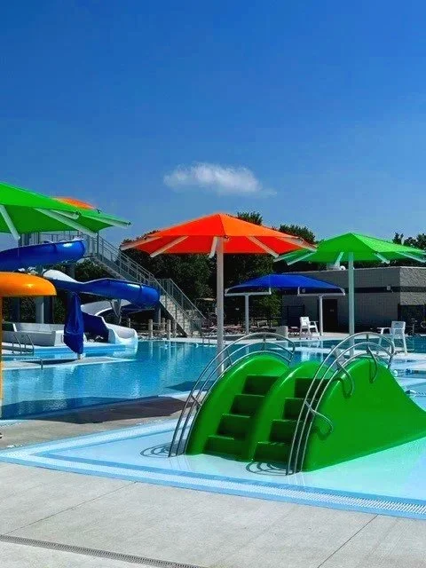 Colorful umbrella shade structures over community aquatic facility and pool at Waverly Nebraska — USS shade structures for athletic fields parks and recreation supplier