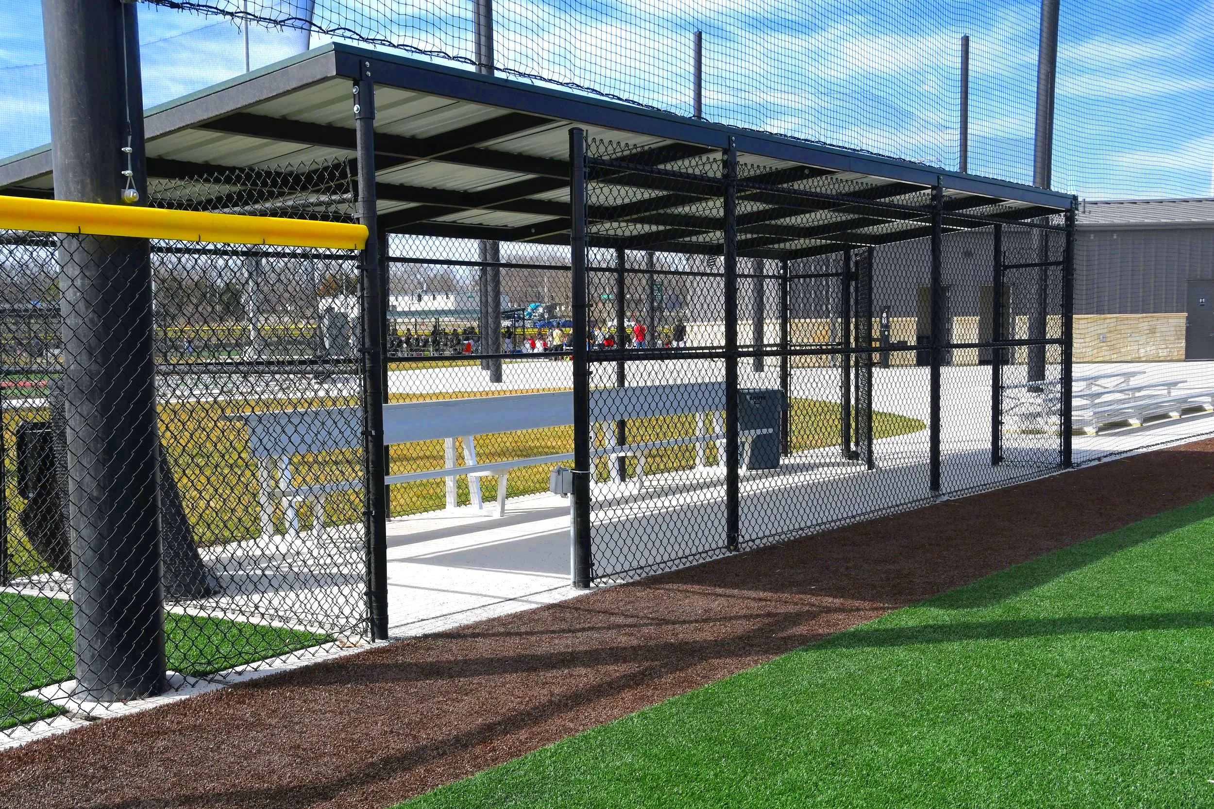 Fielder's Choice Elite baseball dugout with barrier netting bench seating and yellow foul pole at Sandhills Global Sports Complex in Lincoln Nebraska — USS baseball dugout supplier