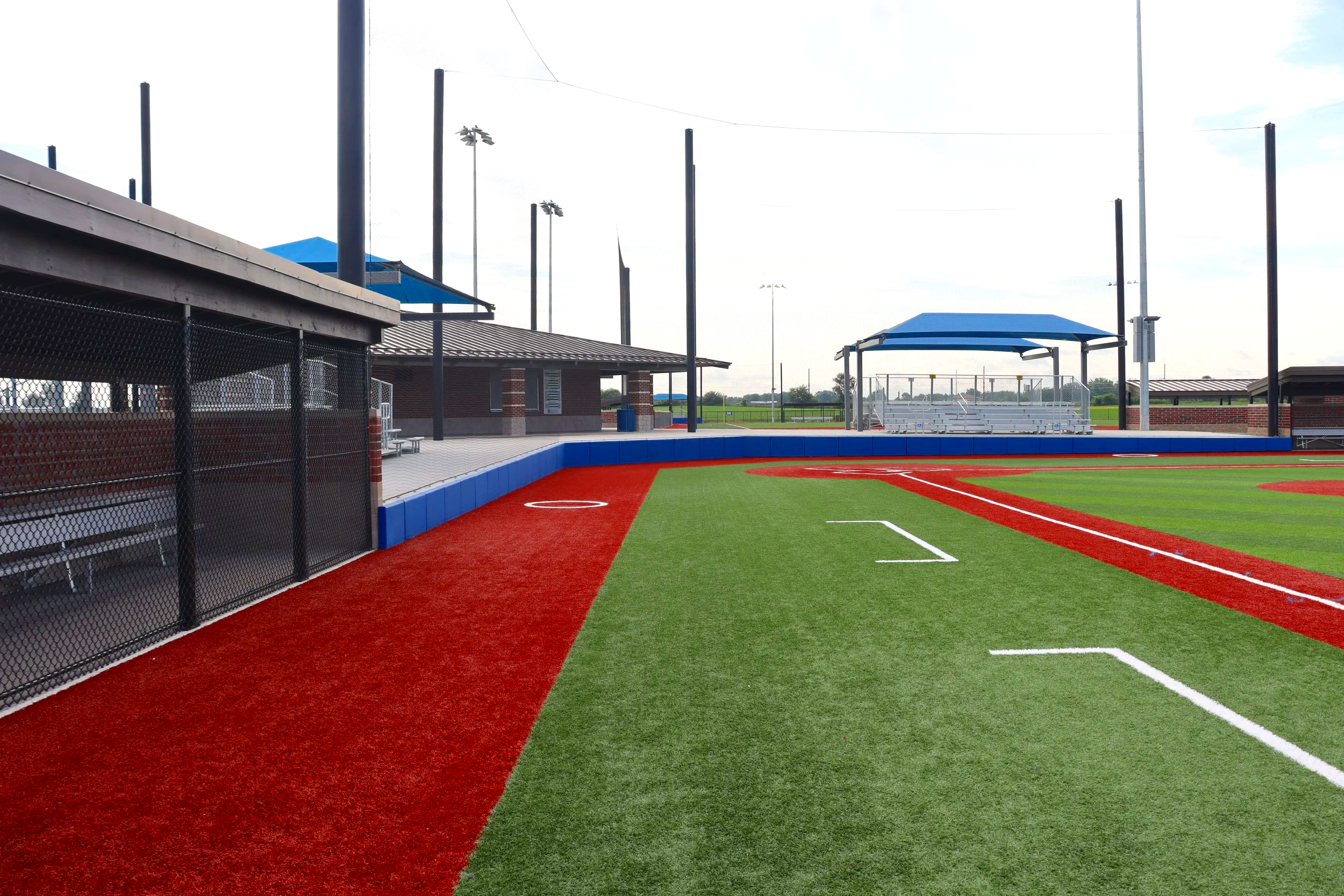 Youth baseball field with dugouts, shade structure, and fence cap at little league complex
