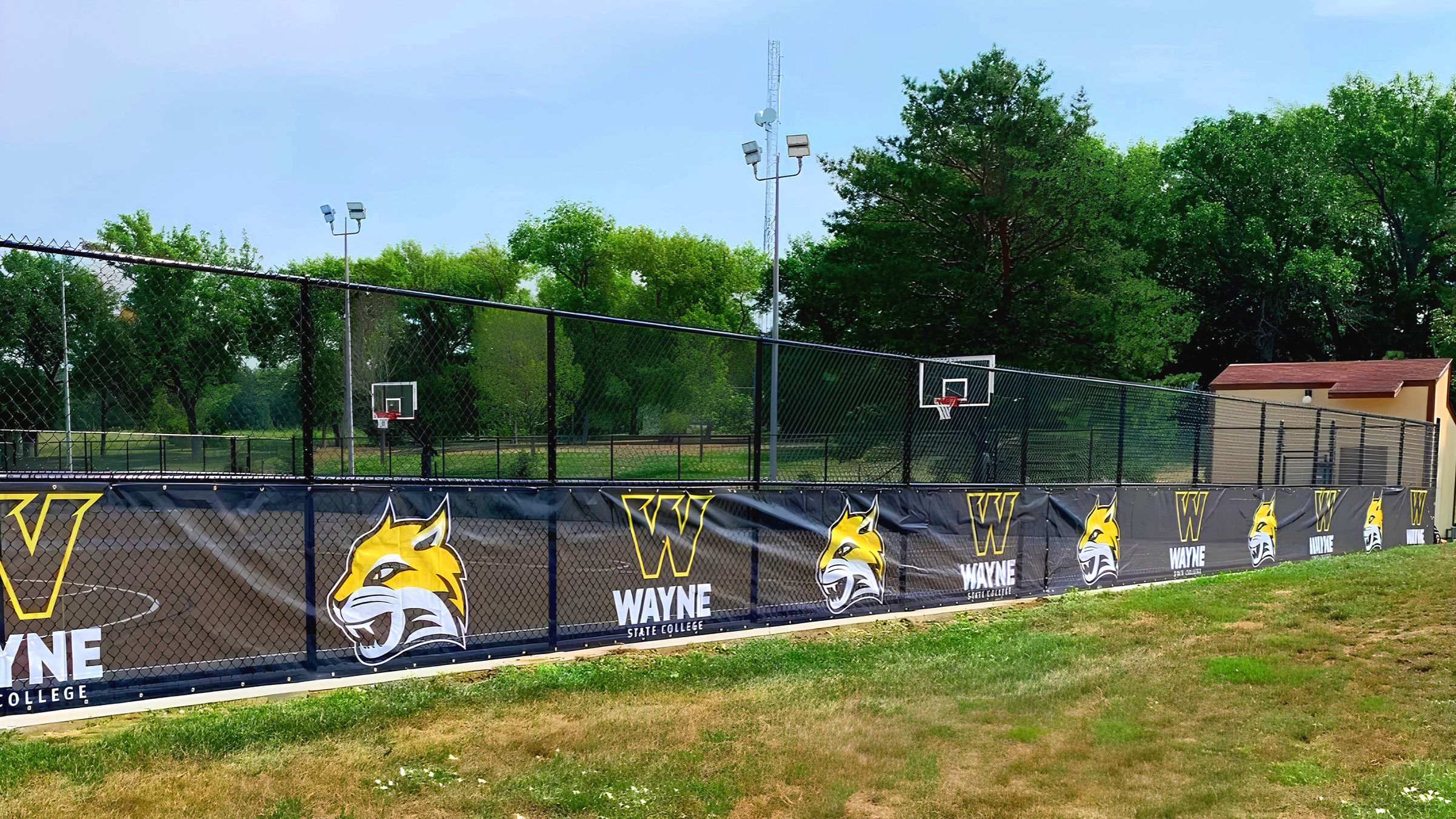Custom branded windscreen with Wayne State College Wildcats graphics on athletic facility fence