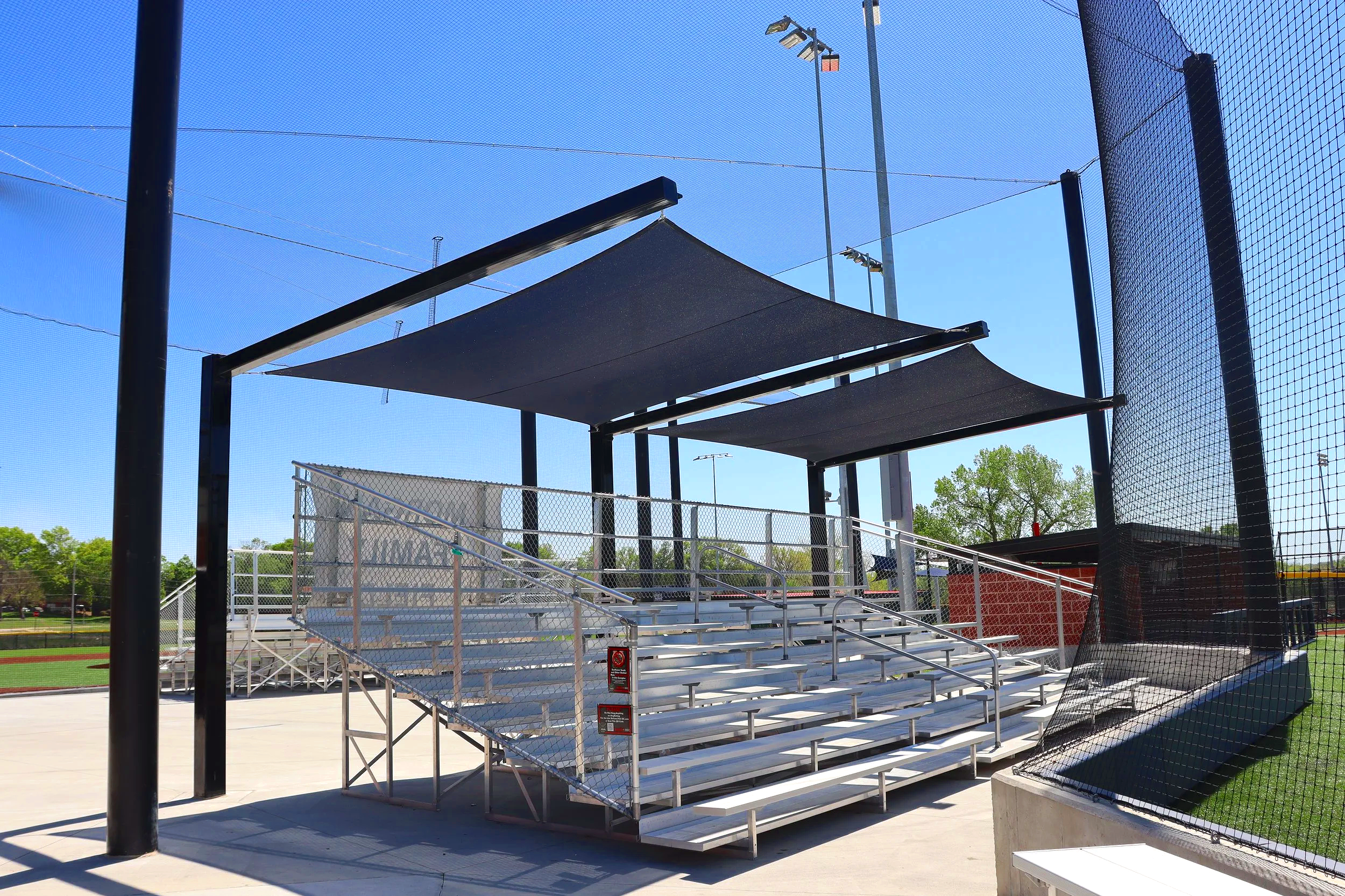 Aluminum bleachers with shade structure canopy at outdoor baseball field — USS aluminum bleachers and shade structures supplier for schools parks departments and athletic complexes