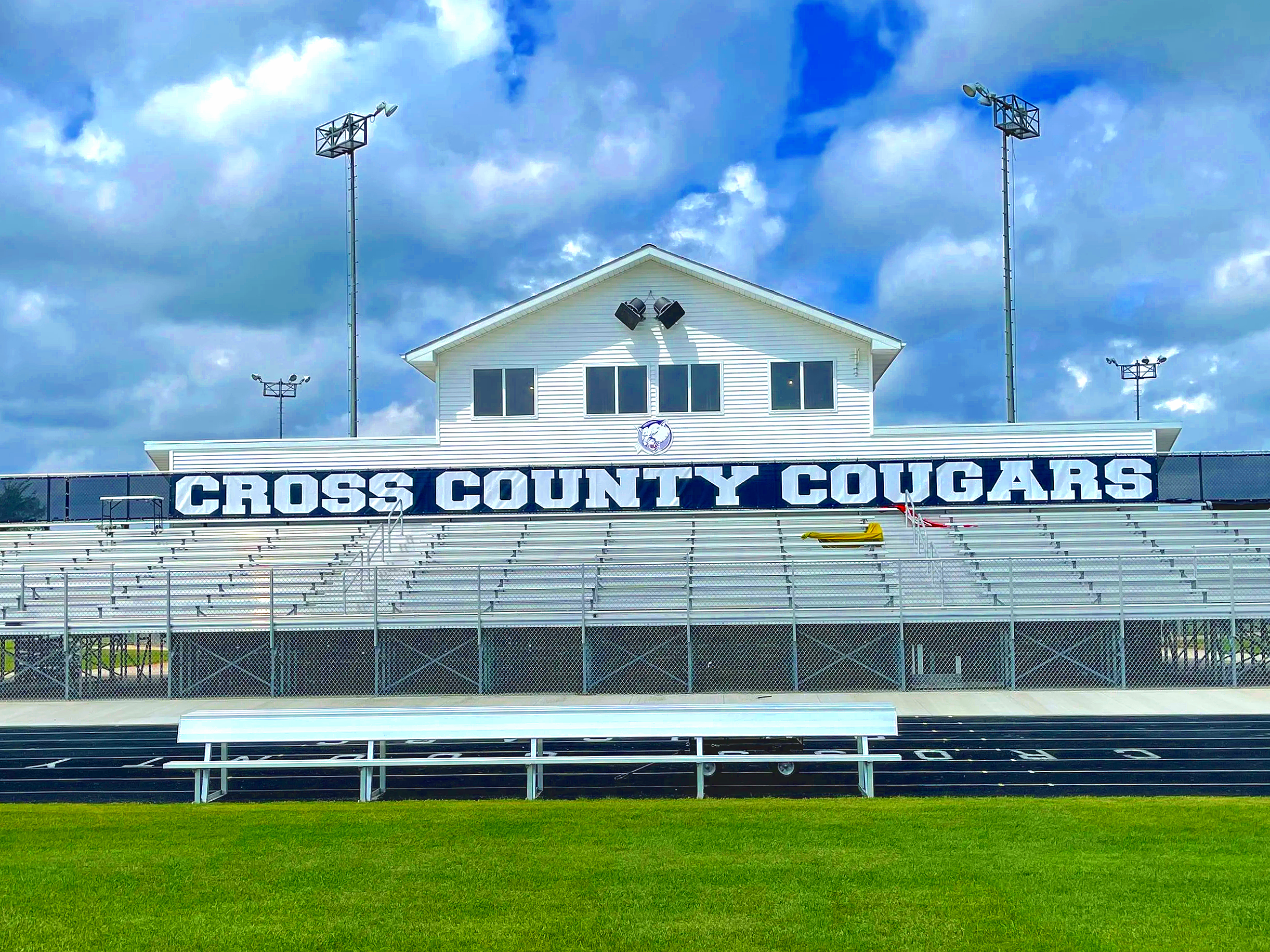 Custom bleacher wrap branding for Cross County Cougars athletic facility with press box and stadium lighting