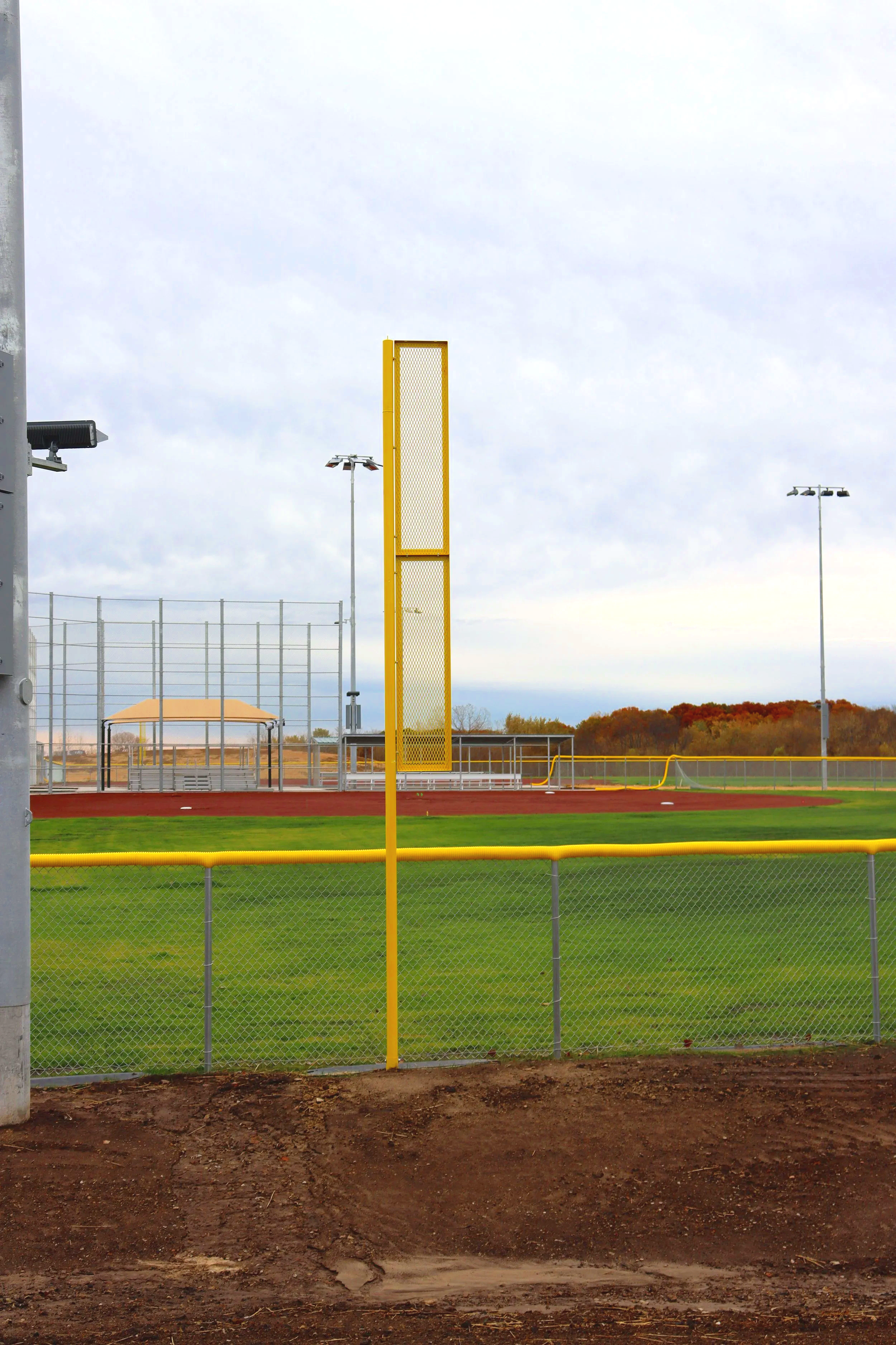 Yellow baseball foul pole installed at athletic baseball facility in Cameron Missouri with dugouts bleachers and red warning track — USS baseball foul pole supplier
