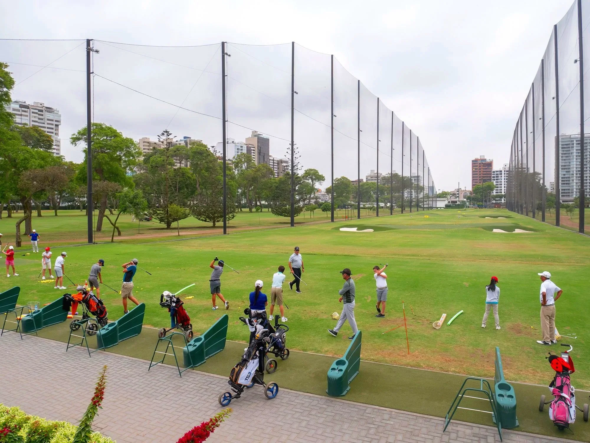 Golfers at driving range with tall containment netting system at golf facility in Lima Peru