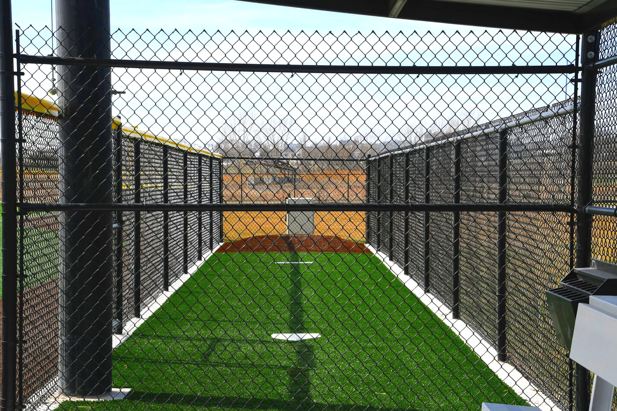 Portable pitching mound in outdoor collegiate baseball batting cage with chain link netting enclosure and synthetic turf — USS portable pitching mound supplier for college athletic programs