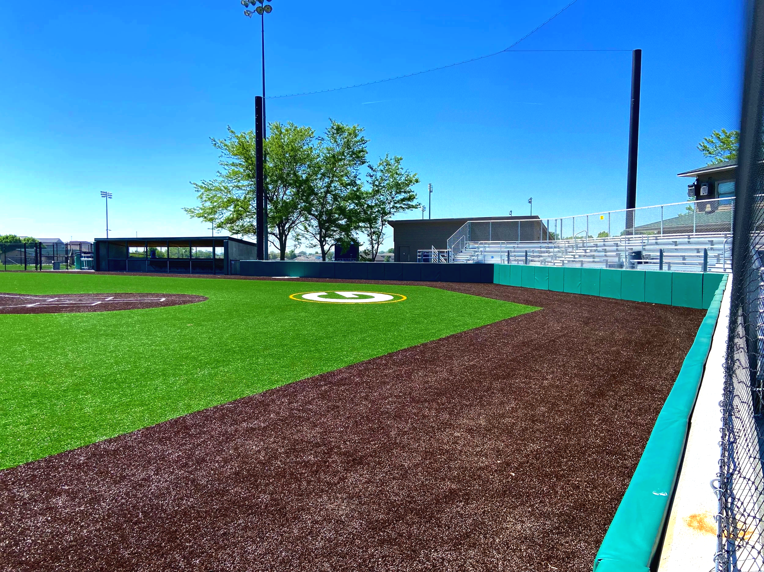 High school baseball field with artificial turf warning track and fence padding at Gretna High School in Gretna Nebraska