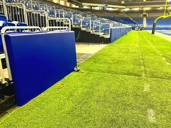 Blue sideline wall padding installed along full football field sideline at the Alamodome in San Antonio Texas — USS sports field padding supplier for professional and collegiate athletic facilities
