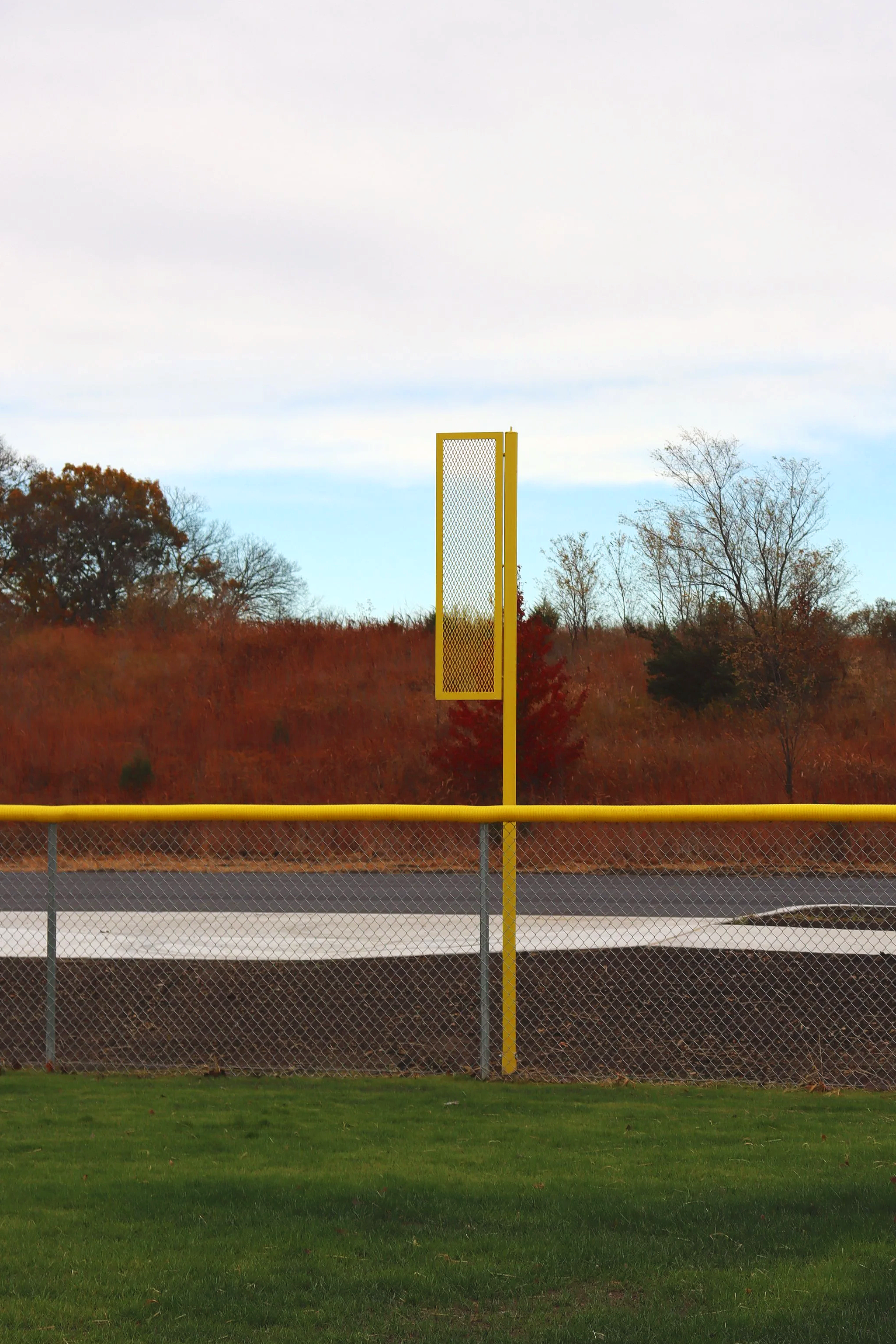 Yellow baseball foul pole mounted on outfield fence line at athletic baseball facility — USS baseball foul pole supplier for high school programs parks departments and athletic complexes nationwide