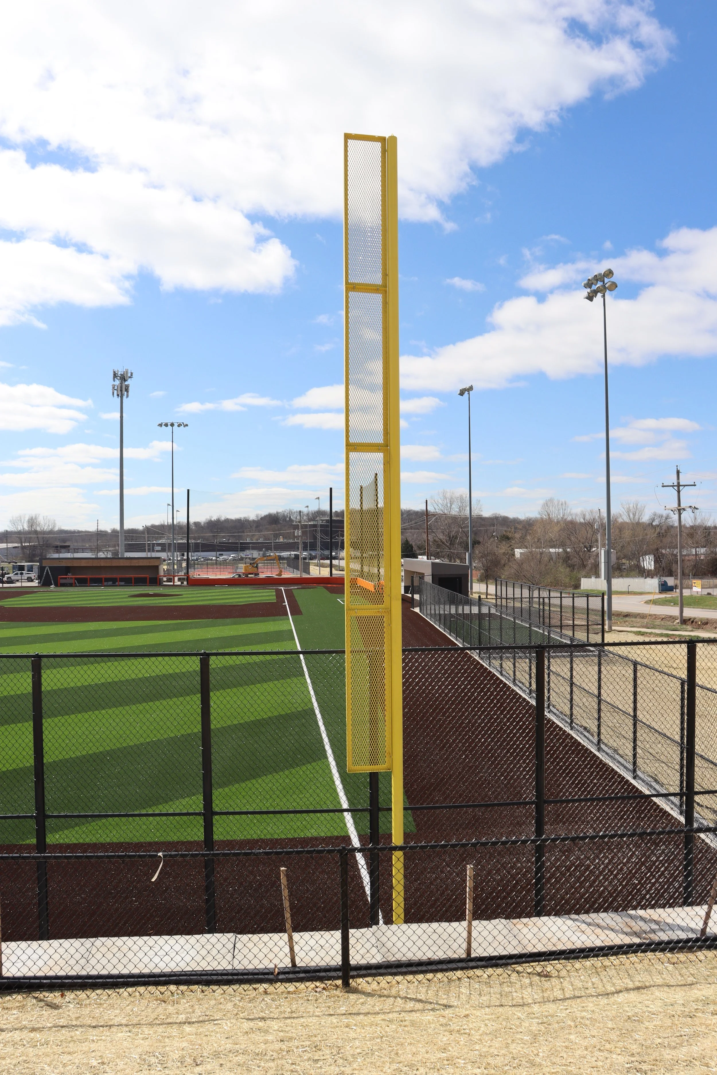 Yellow baseball foul pole installed at Bonner Springs Kansas athletic baseball facility with synthetic turf and red warning track — USS foul pole supplier for high school programs parks departments and athletic complexes nationwide
