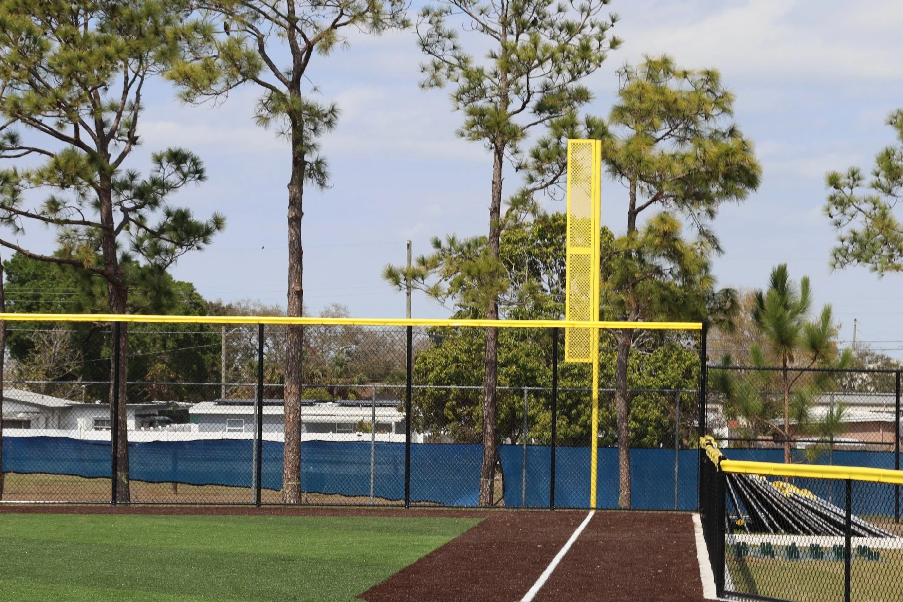 Yellow foul pole at baseball field with chain link fence and palm trees