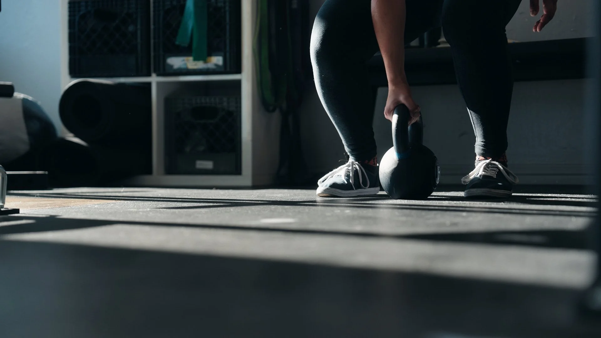 Close up feet and hands of client lifting a kettle bell at Bay Strength gym in Berkeley, CA