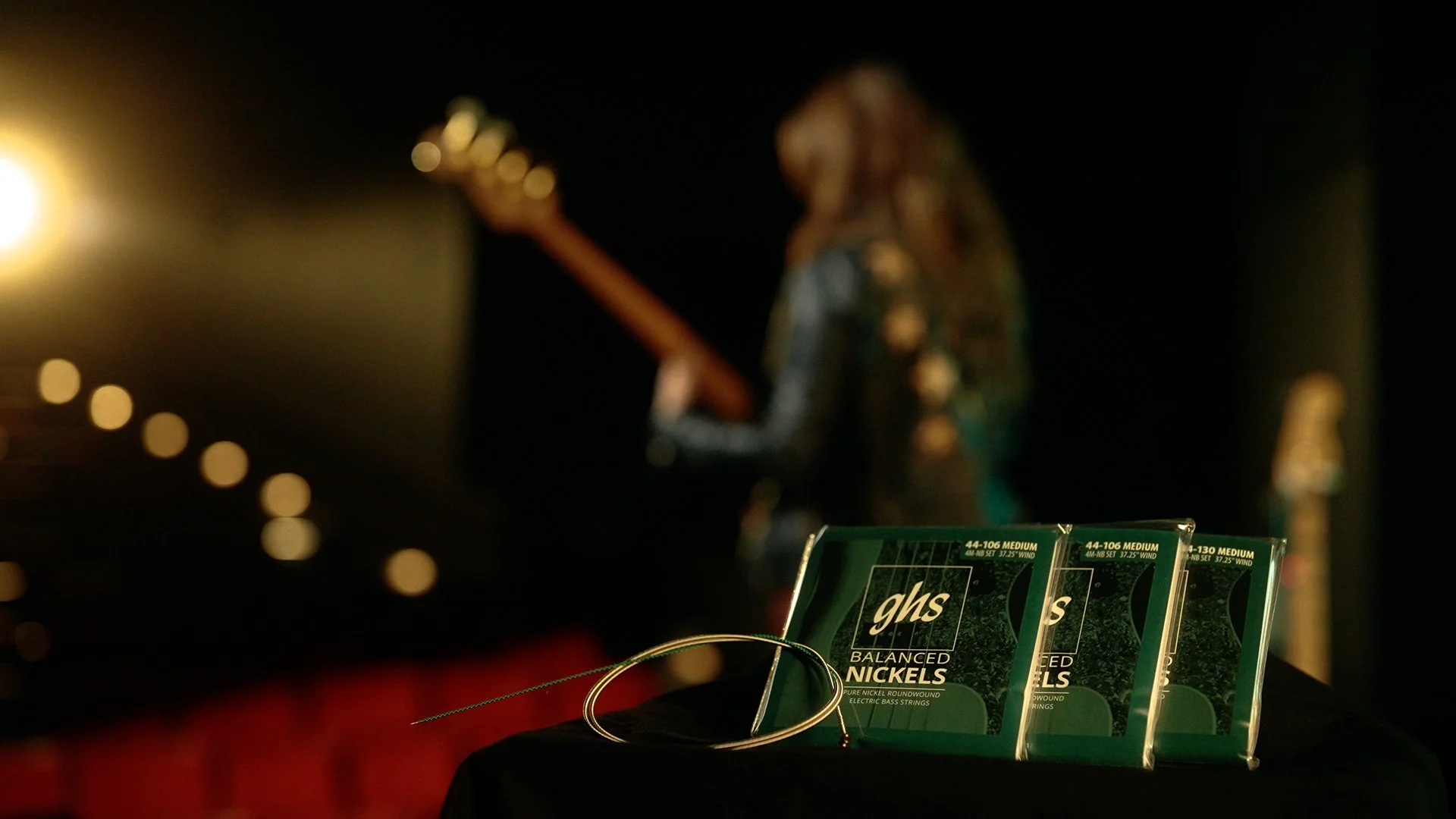 Musician Angeline Saris playing  the bass with a pack of GHS Strings in the foreground 