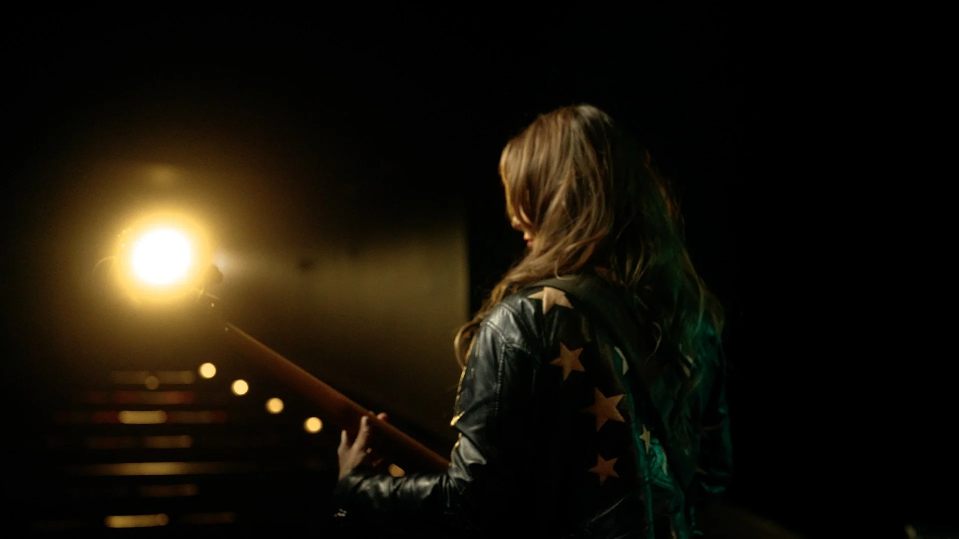 Musician Angeline Saris playing the bass in front of spot light 