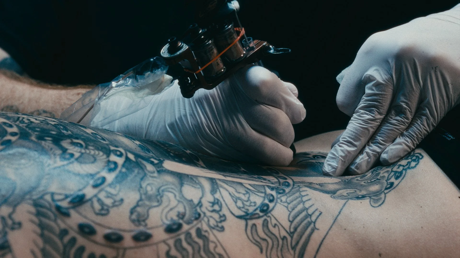 Tattoo artist working on a back piece at Eye of The Tiger Tattoo shop in San Francisco, CA
