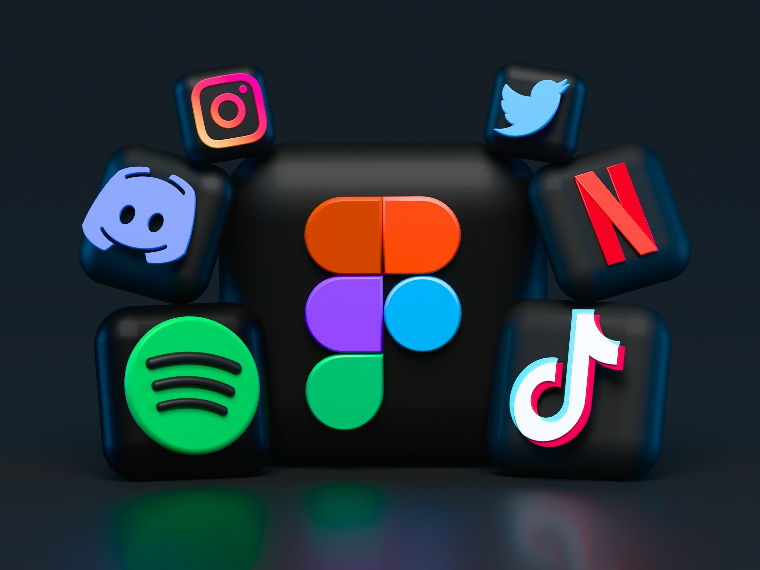 Black cubes with colorful logos of social media and apps, including Instagram, Twitter, Discord, Netflix, Spotify, TikTok, and others, arranged on a dark background.